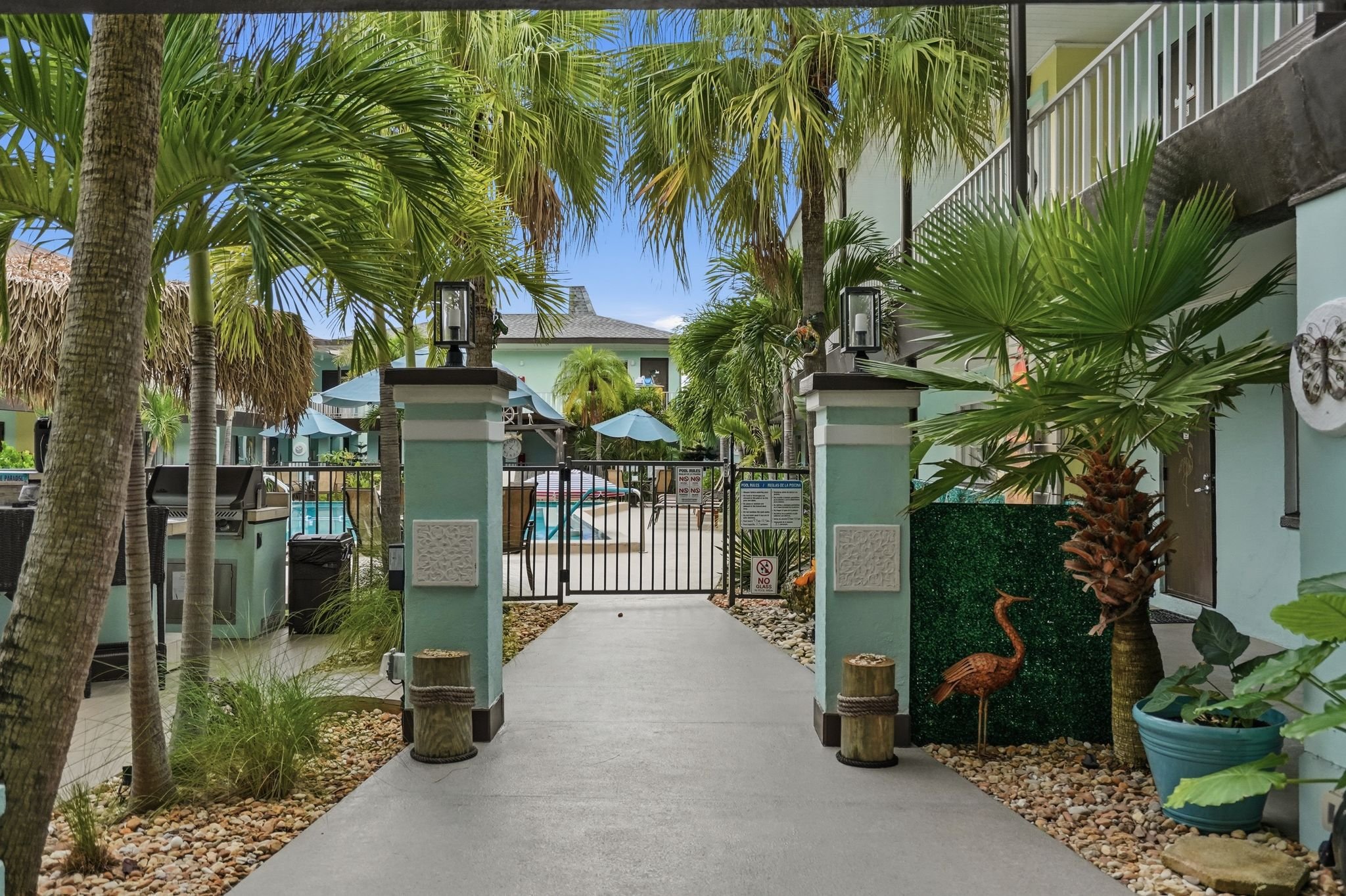 Palm-lined walkway leading to the gated pool courtyard at Island House Resort Hotel