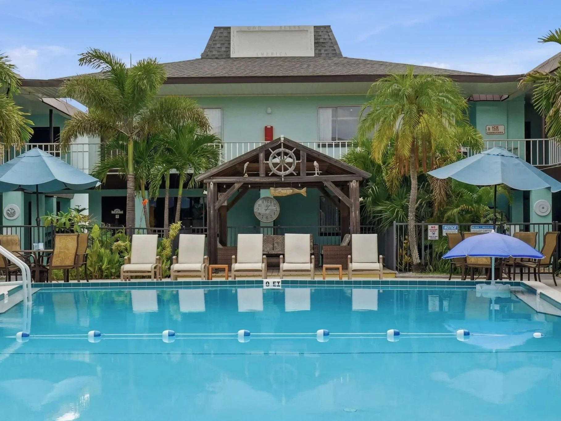 Poolside gazebo with nautical ship's wheel and lounge chairs at Island House Resort Hotel