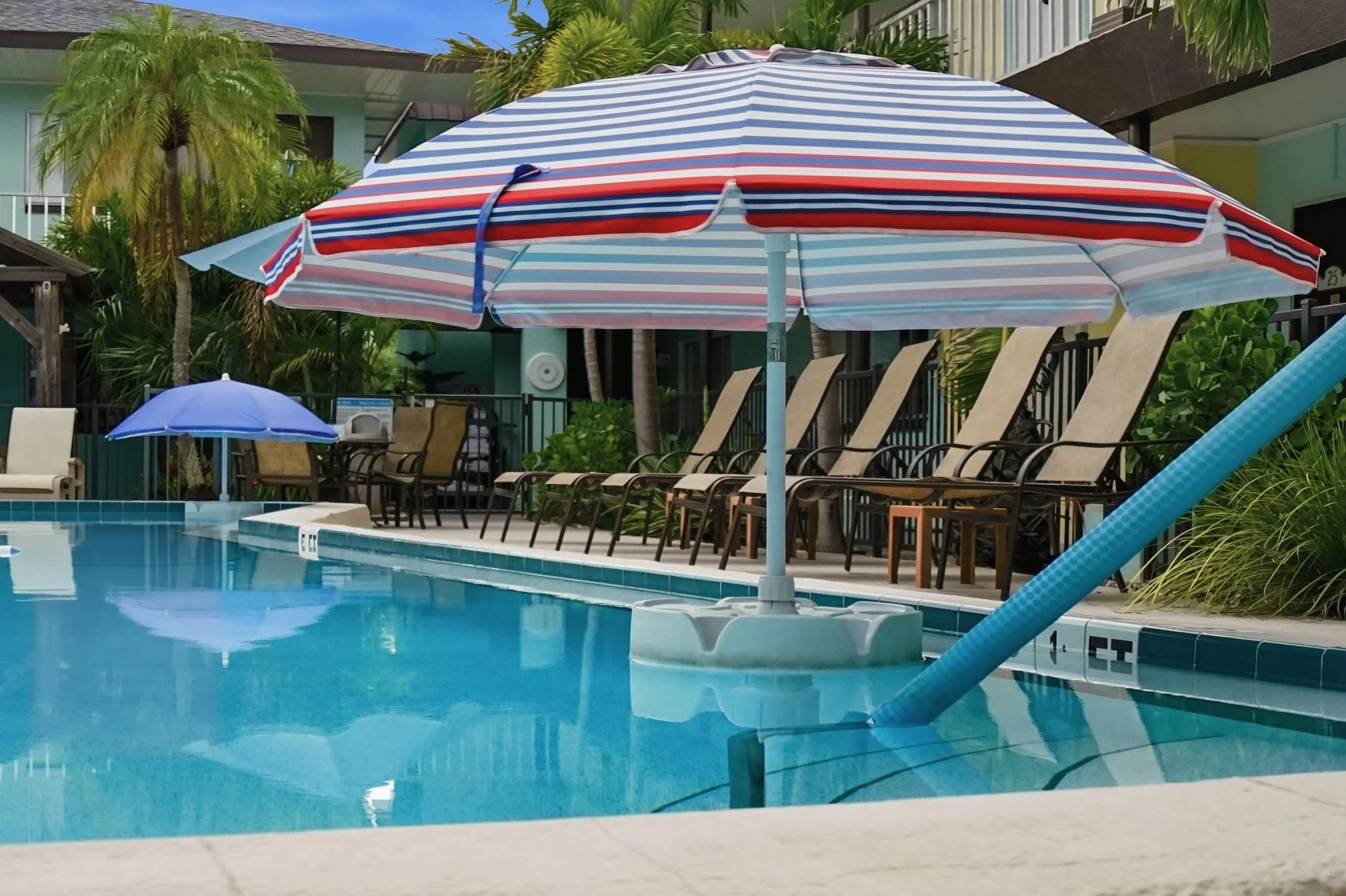 Striped umbrella shading the sun shelf in the outdoor pool at Island House Resort Hotel