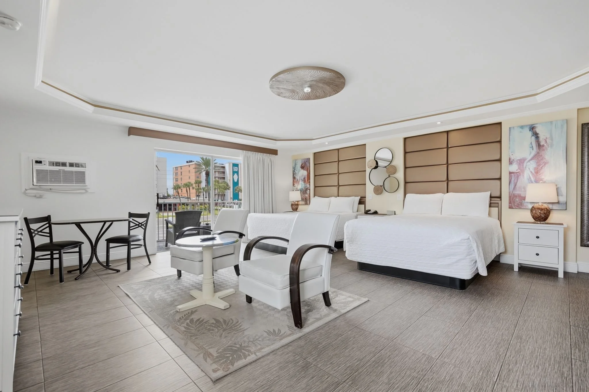 Spacious guest room with two beds, dining table, sitting area and balcony access