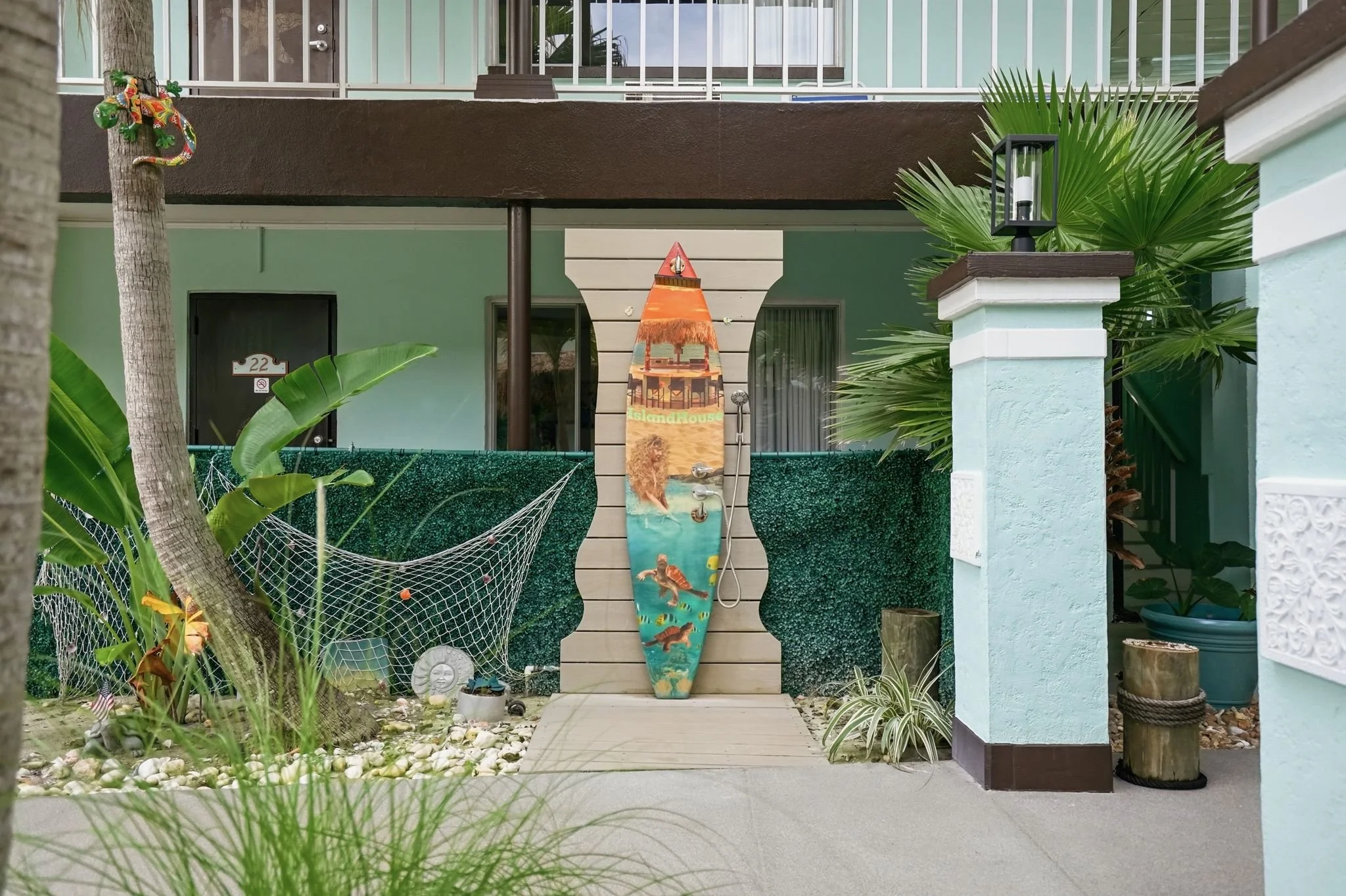 Outdoor rinse shower with hand-painted Island House surfboard at Island House Resort Hotel