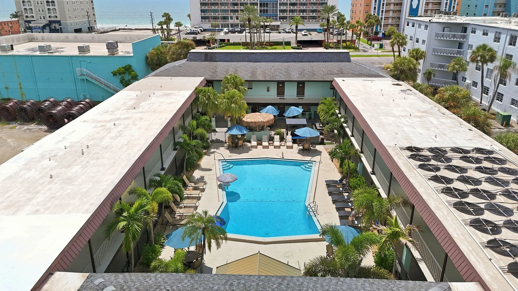 Aerial view of the courtyard pool and guest buildings with the Gulf beyond, Island House Resort Hotel