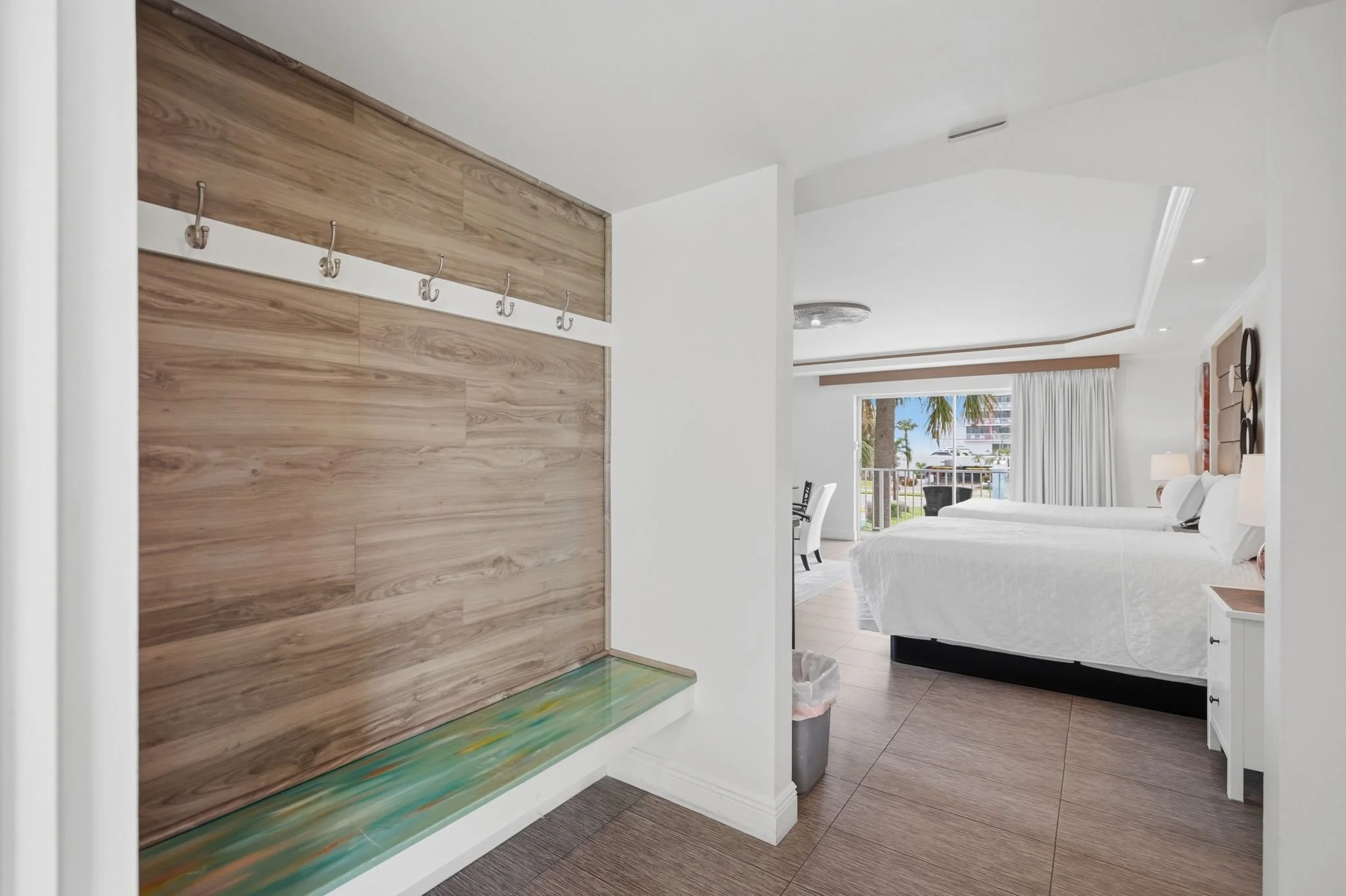 Entry with coat hooks and glass-topped bench in a balcony suite at Island House Resort Hotel
