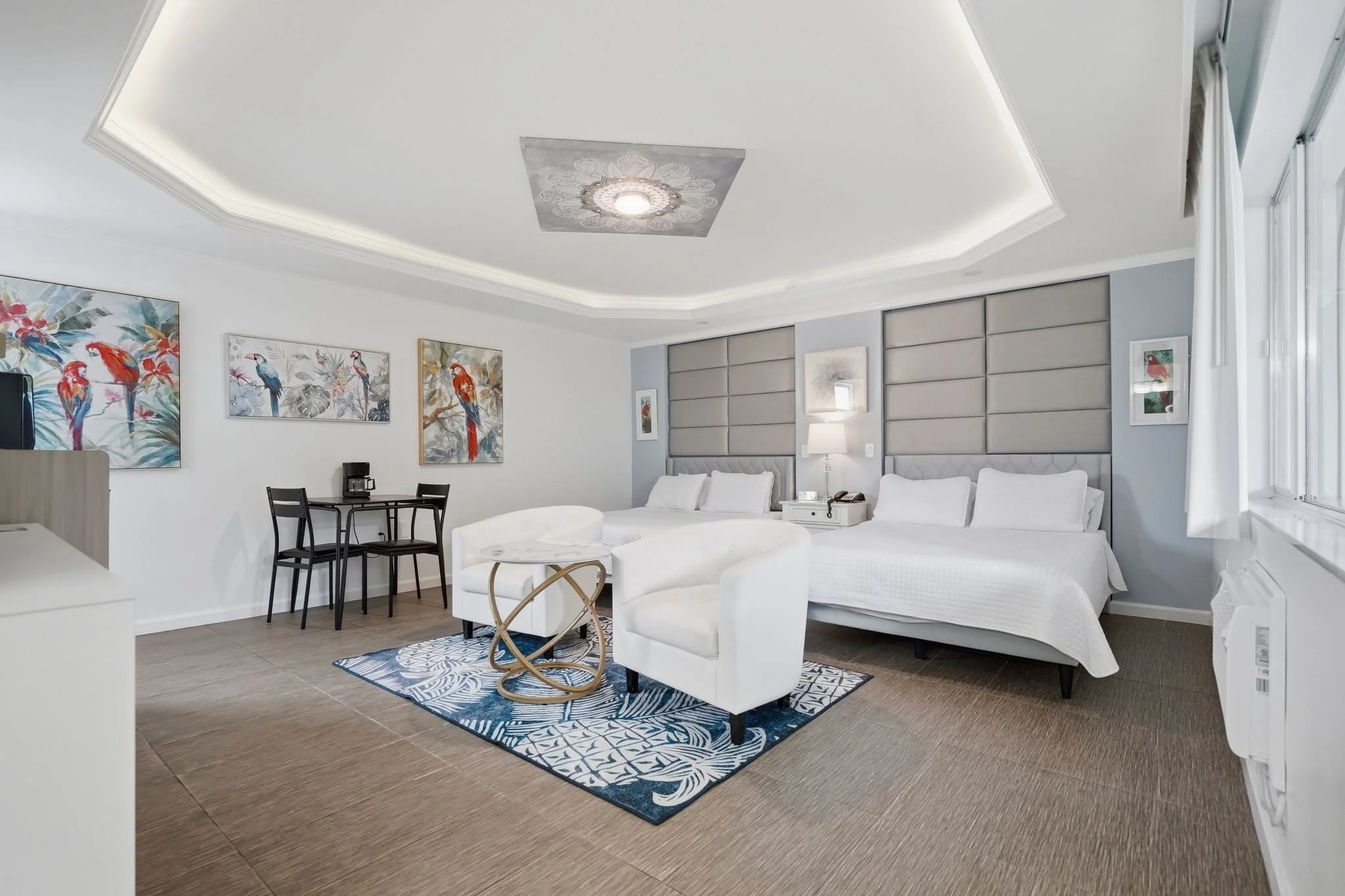 Standard Two Queen room with sitting area, dining table and tropical parrot artwork
