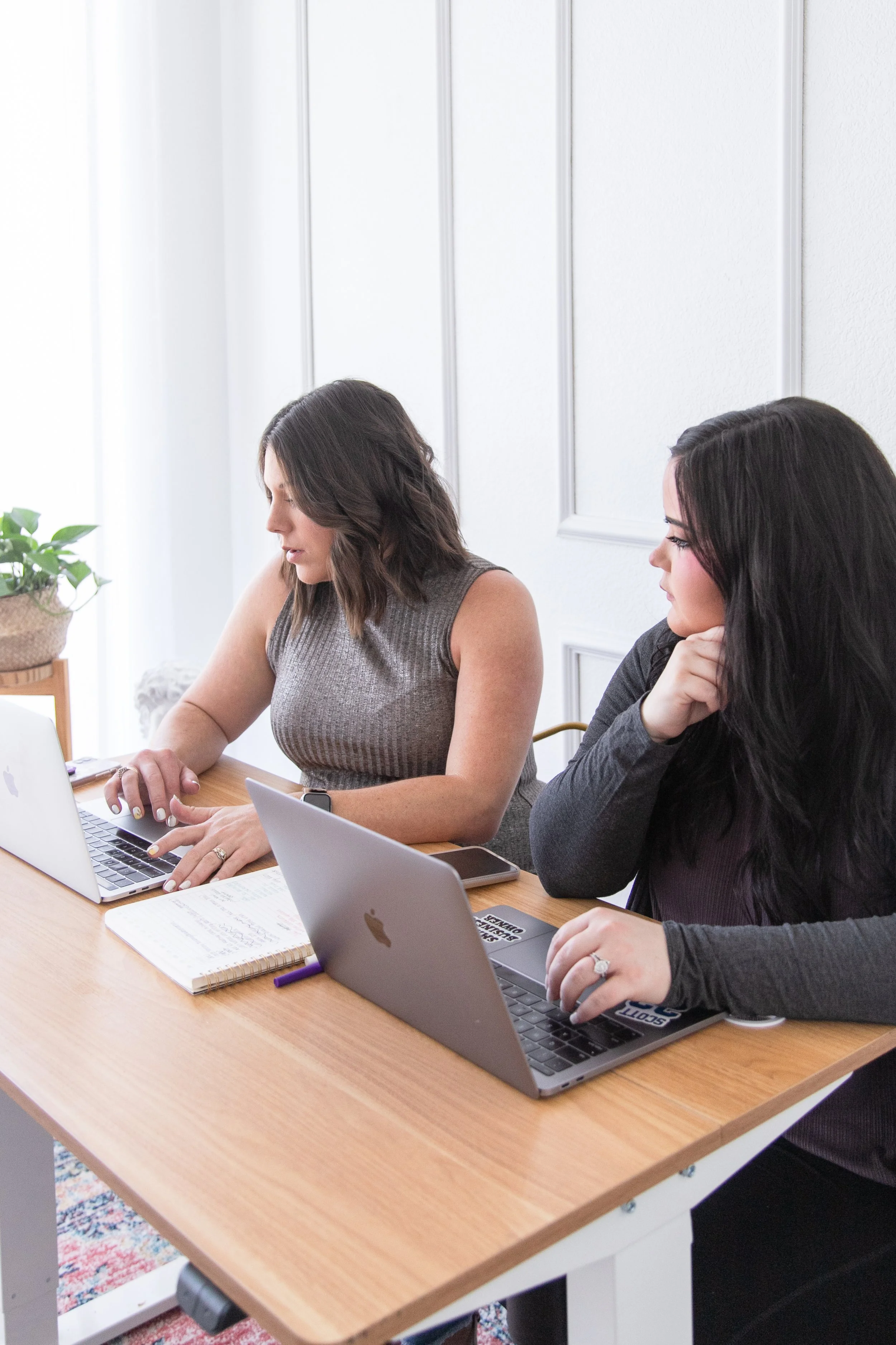 Business strategist AnnMarie Rose working with a coaching client at a table with two laptops open