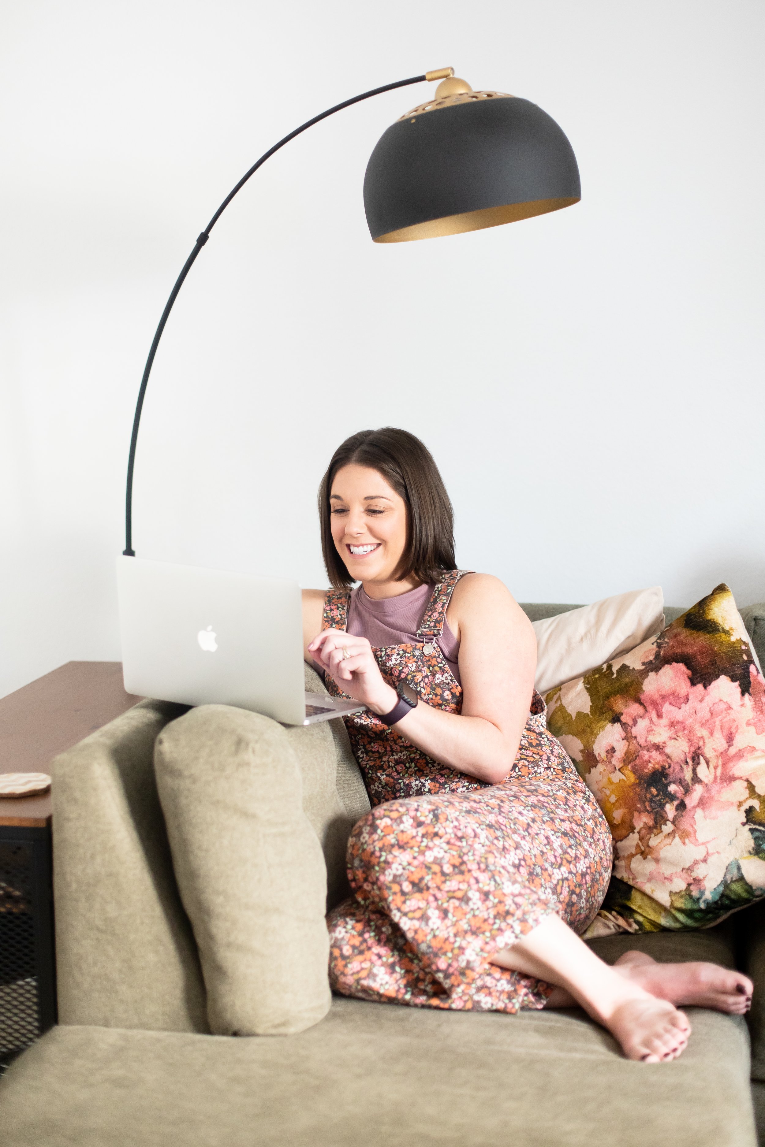AnnMarie Rose, business strategist, sitting on an olive couch working from her laptop