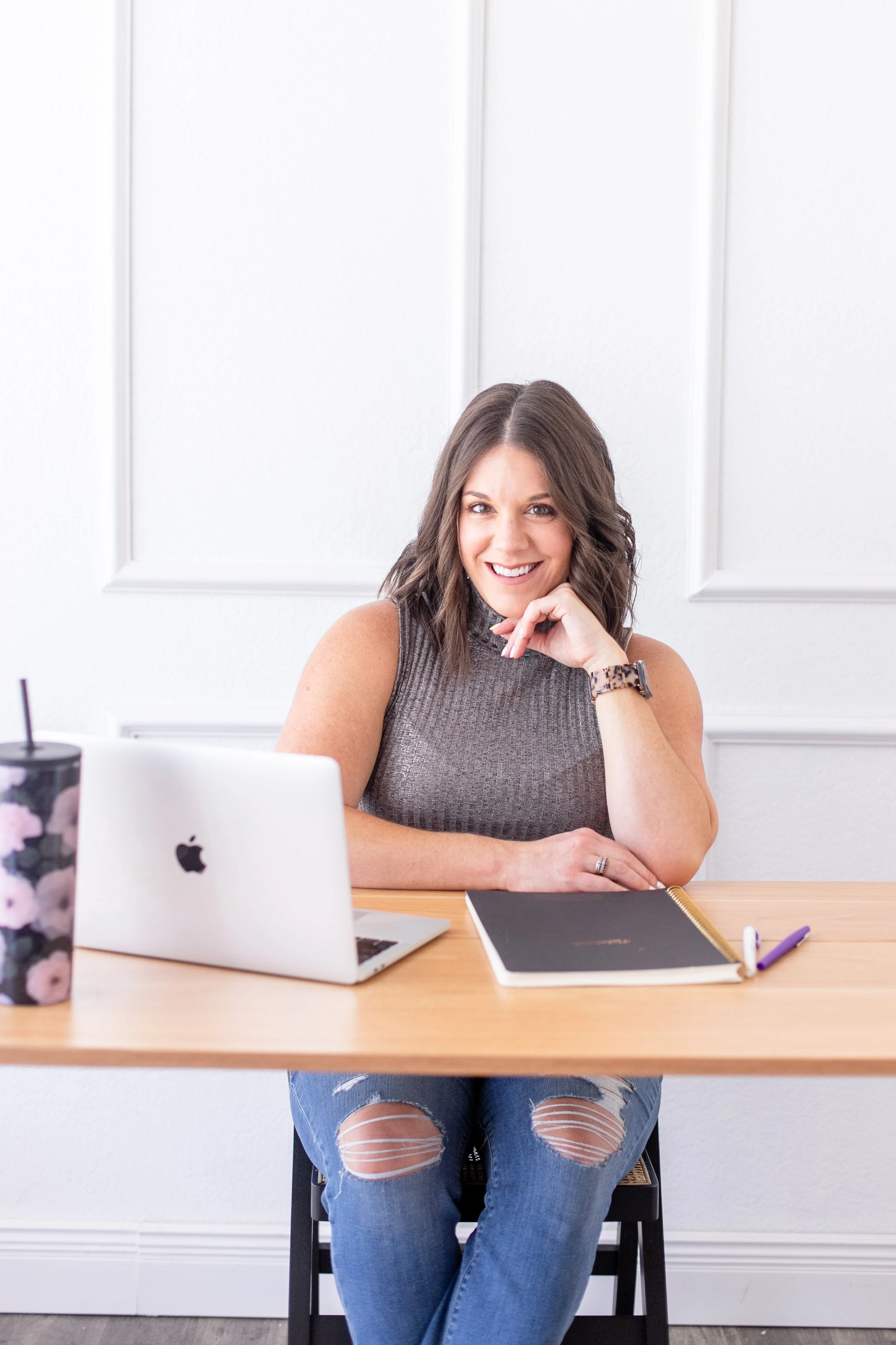 AnnMarie Rose, business strategist, sitting at desk with an open laptop, tumbler, notebook, and pens