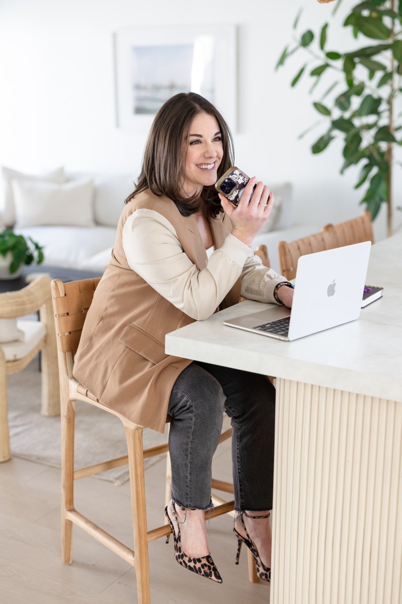 AnnMarie Rose, business strategist, sitting at a counter, working on a cell phone and laptop