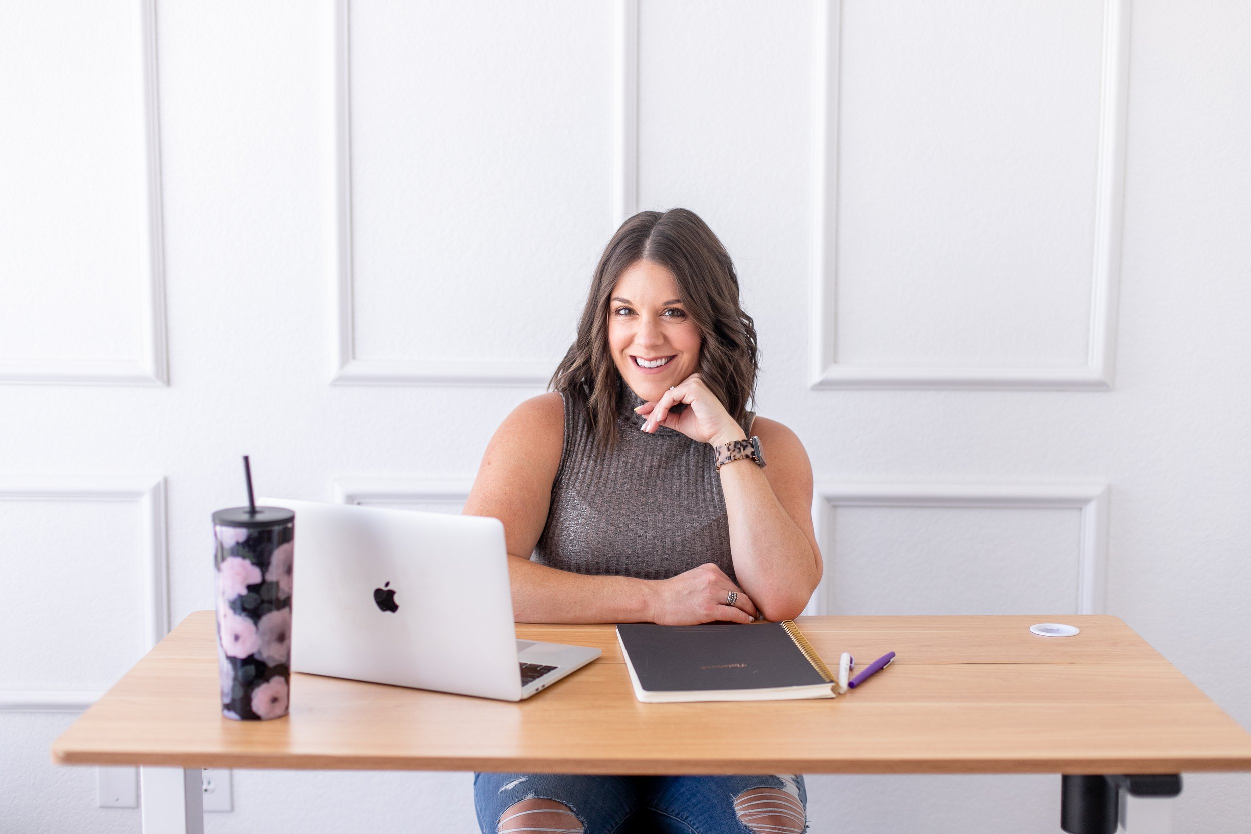 AnnMarie Rose business strategist sitting at a large desk with a laptop, notebook, and cup