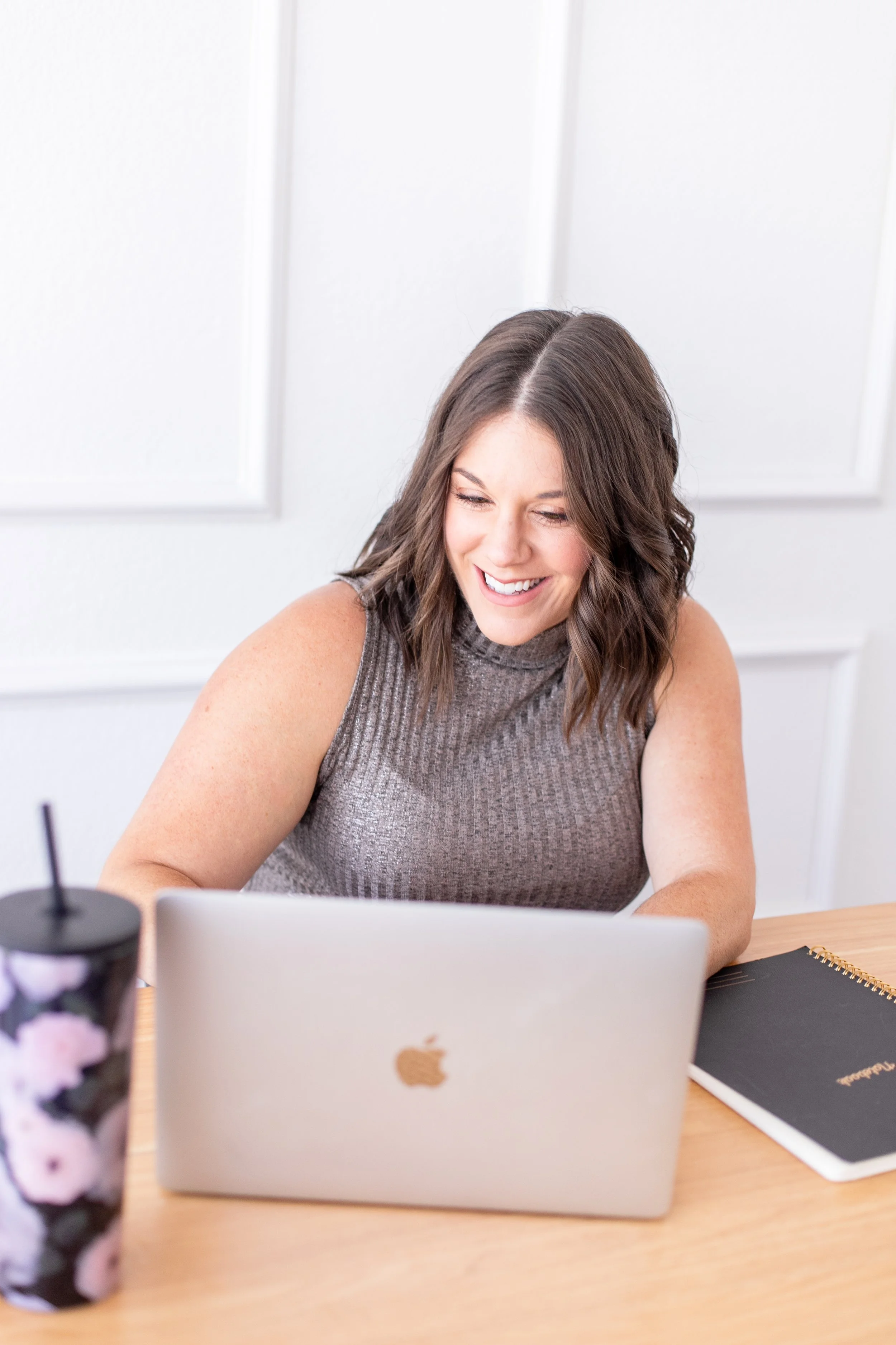 AnnMarie Rose, scaling strategist, working at a desk with a laptop, notebook, and a floral-patterned tumbler