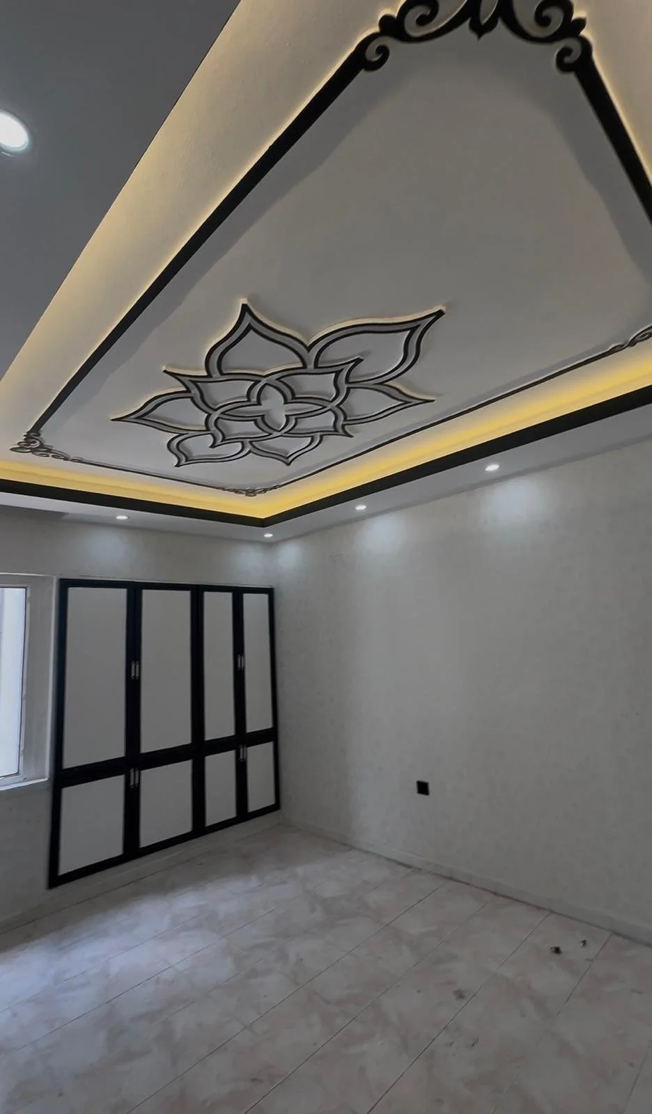 Tavan dekorasyonuyla güzel aydınlatmalı, beyaz duvarlara sahip boş oda.