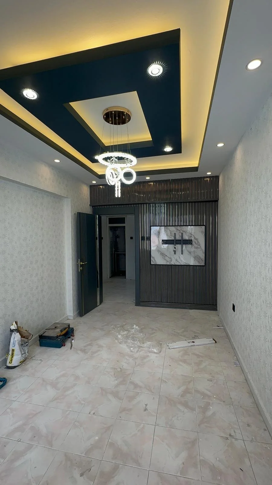 İç mekanda modern tavan tasarımı ve gömme ışıklar, orta seviyede lamba asma ve duvar kaplamasıyla hall
