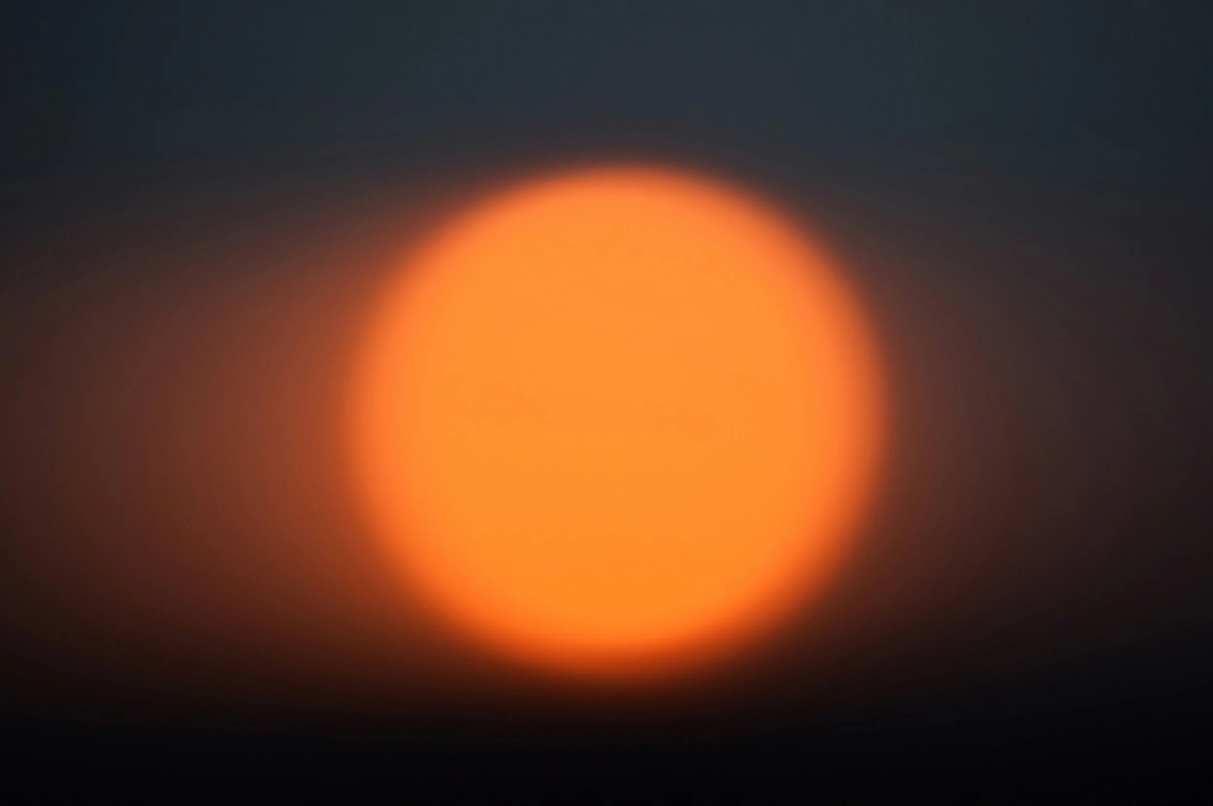 Blurred image of a bright orange light against a dark background.