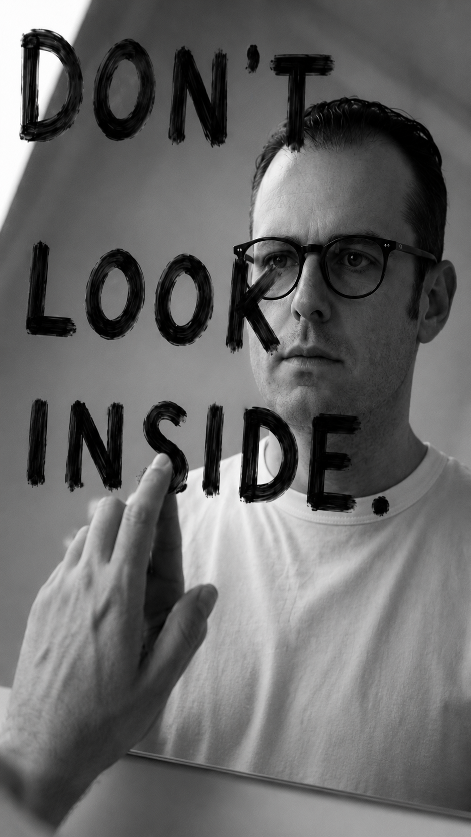 Self-portrait from Floating Strength by Mexican artist Fer Quirarte, facing a mirror inscribed with the words "DON'T LOOK INSIDE," exploring identity, self-perception, and emotional vulnerability.