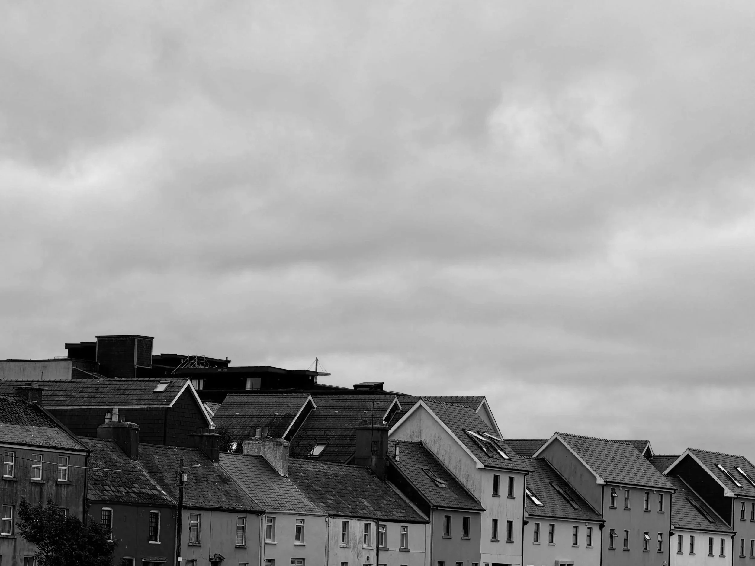 Overcast sky over a row of houses with sloped roofs in an urban neighborhood.