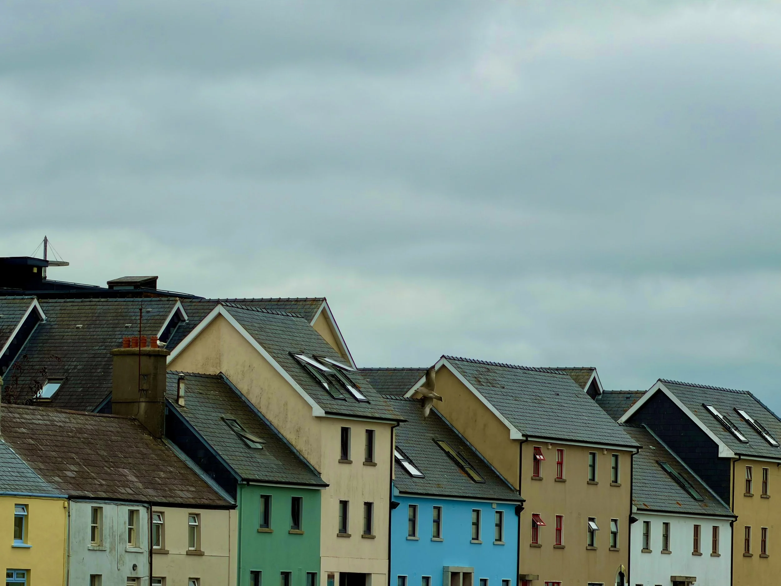 Colorful houses with sloped roofs under a cloudy sky.