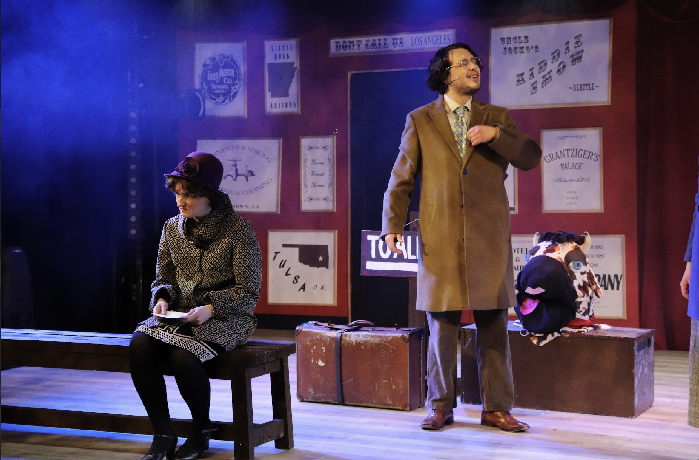 People performing on a stage with vintage posters in the background, including signs and advertisements.