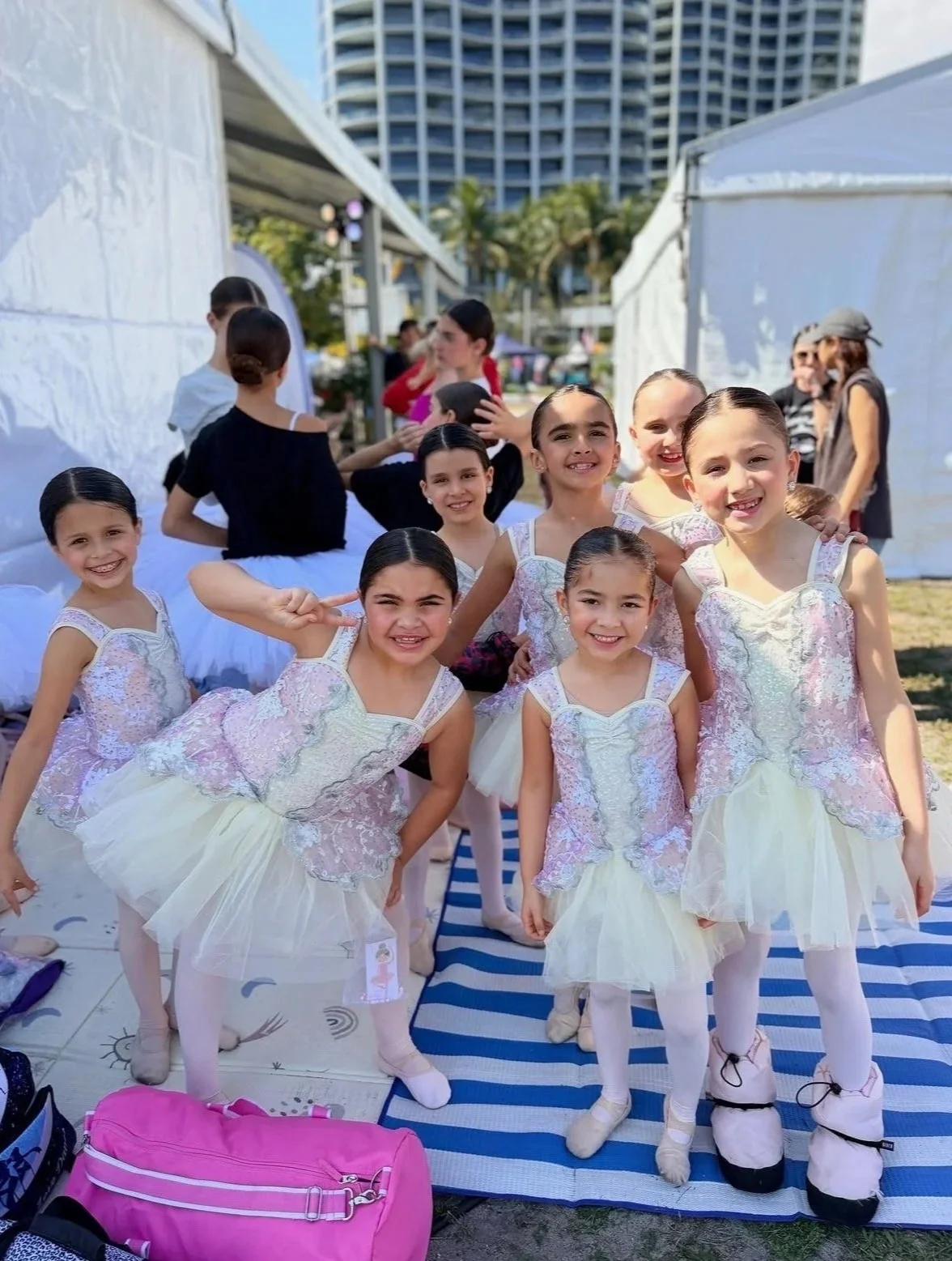 Group of young girls dressed in ballet costumes, posing outdoors at a dance event.