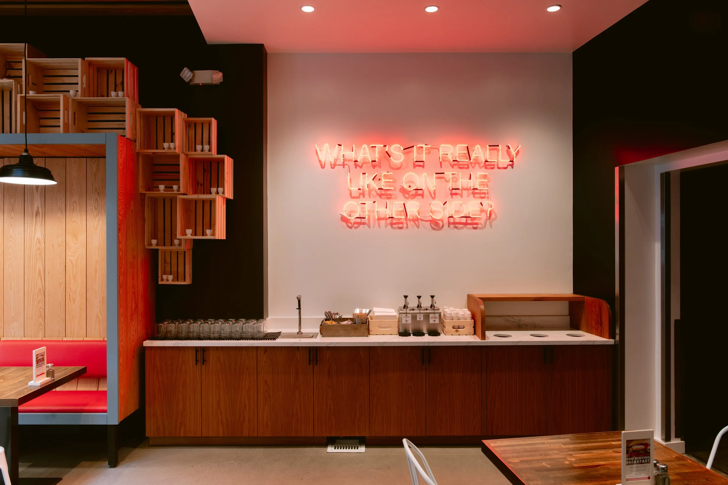 Interior of Proposition Chicken San Francisco with seating near a wooden counter with condiments and silverware.