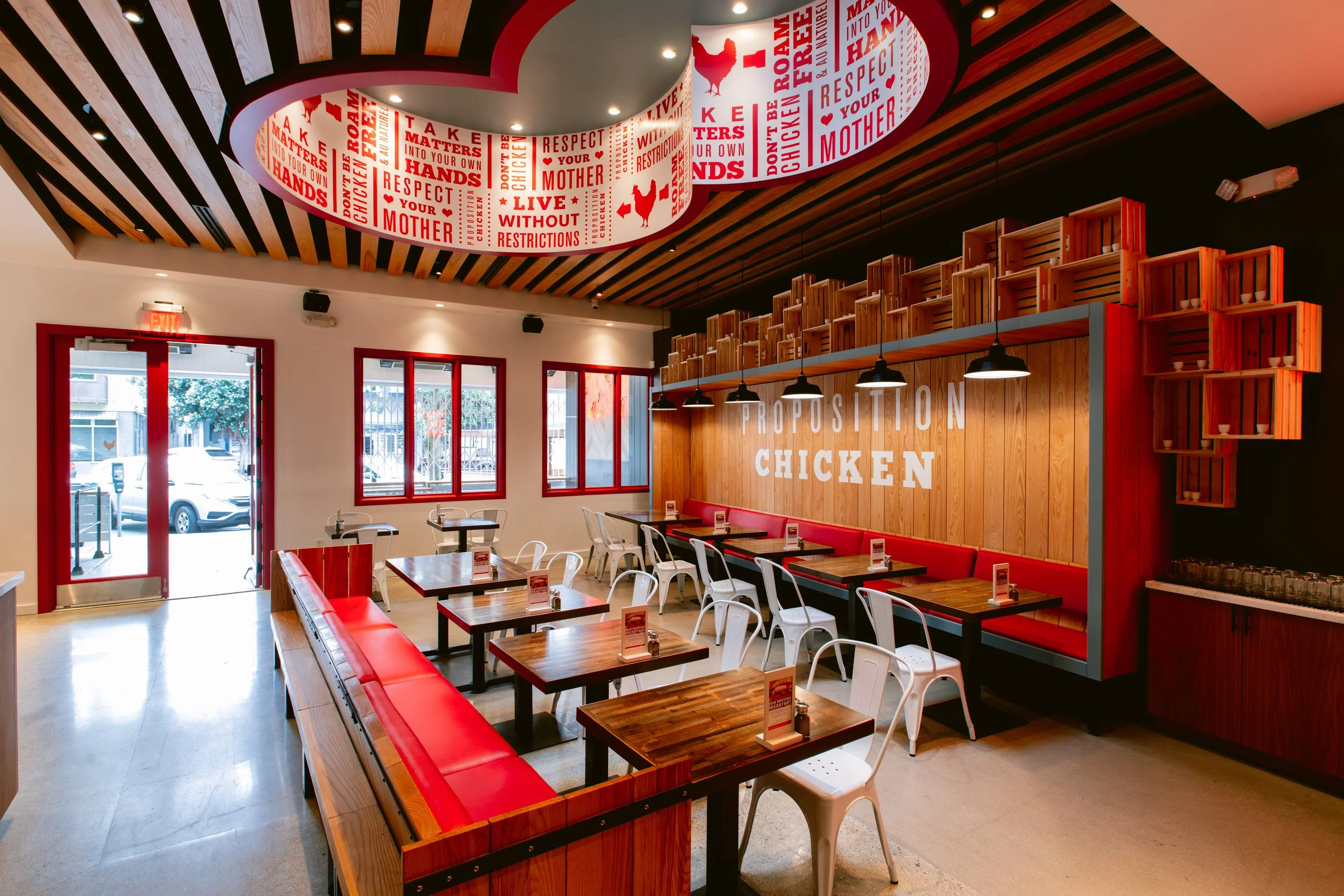 Interior of Proposition Chicken San Francisco - a restaurant with wooden accents, red and white decor, multiple tables and chairs.