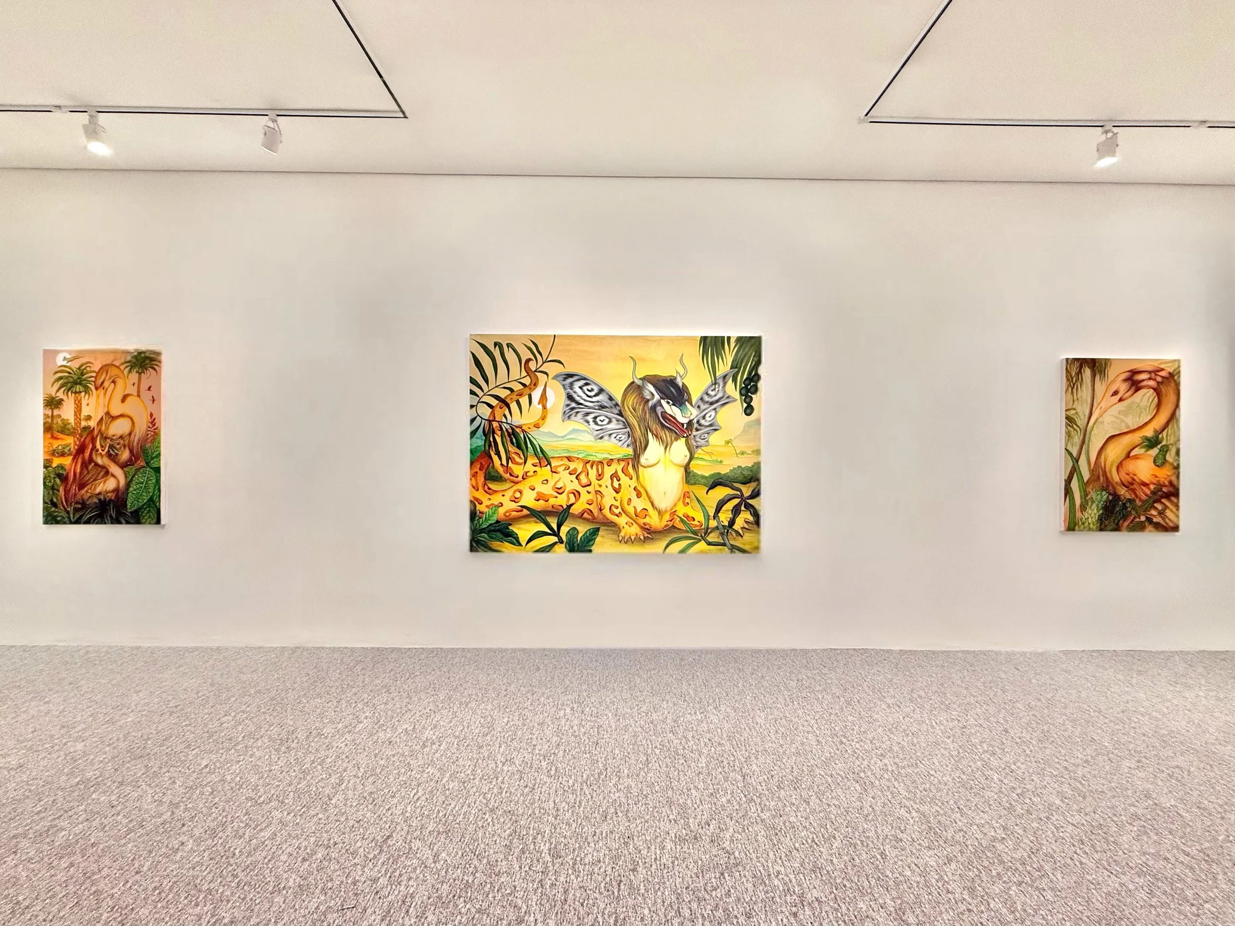 Art gallery wall displaying three colorful paintings, one in the center with a mythical creature, flanked by two other fantasy-themed artworks.