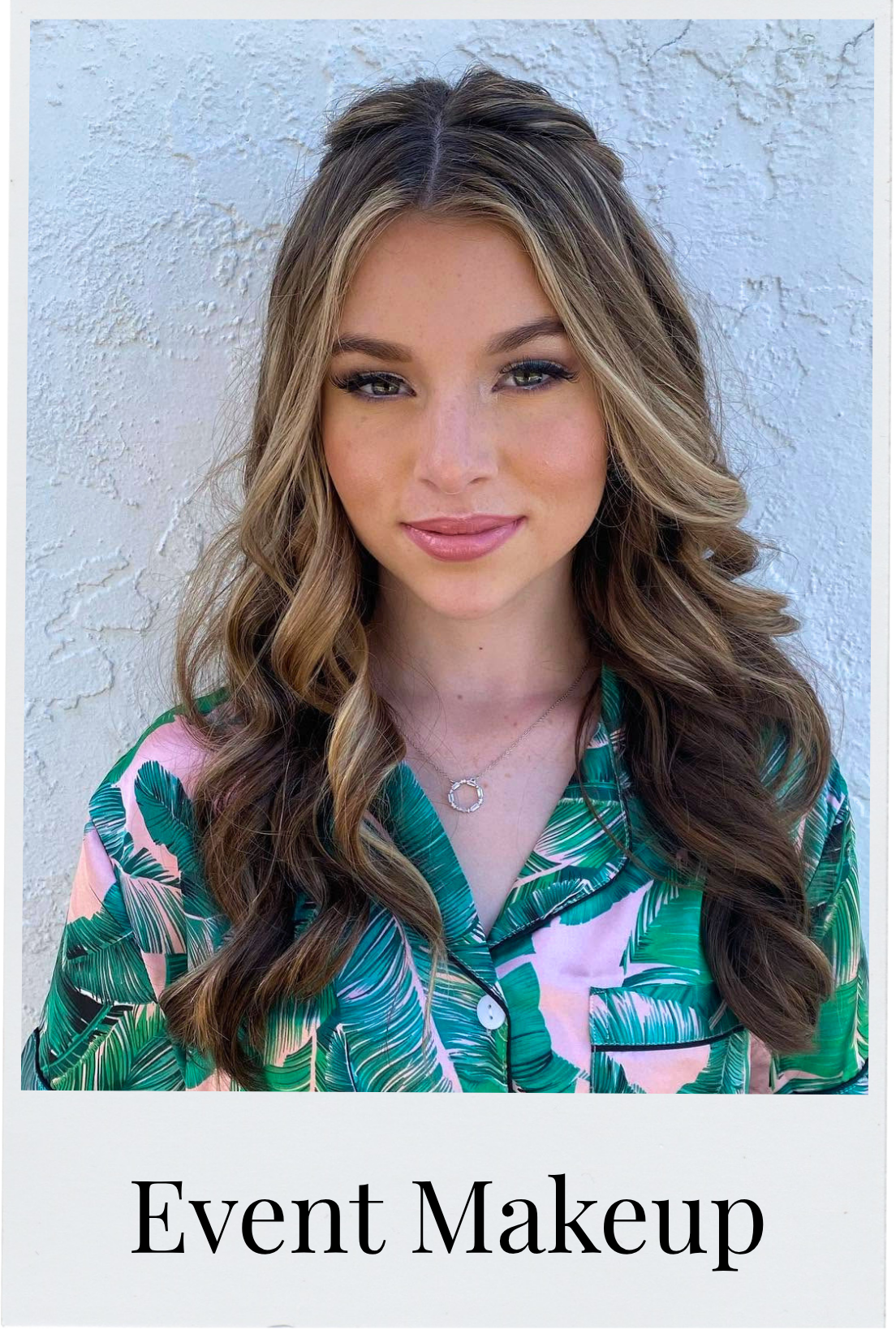 A woman with long wavy hair, wearing makeup, a green and pink tropical print shirt, and a silver necklace with a circular pendant, standing against a textured white wall. Text below reads "Event Makeup."
