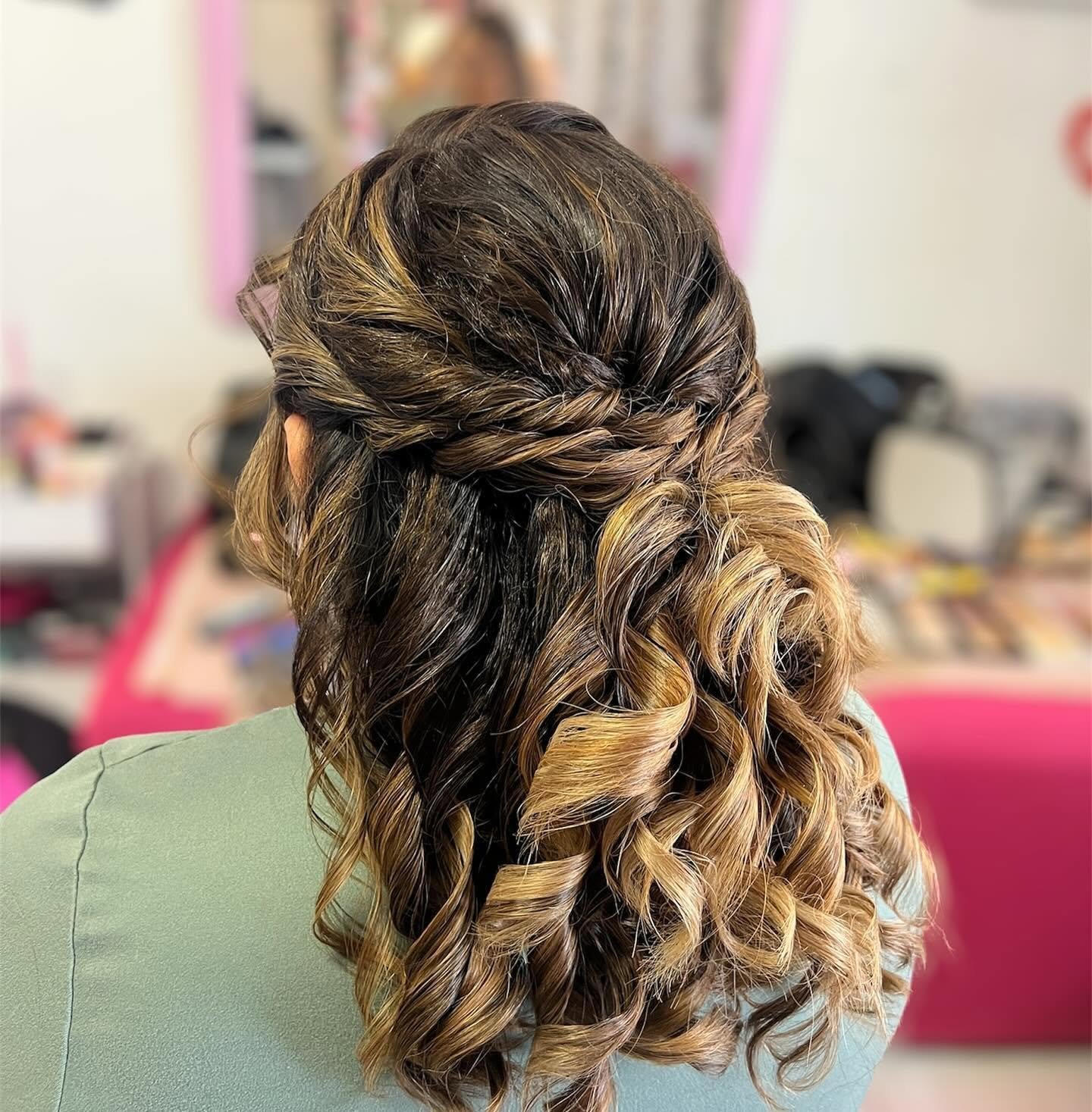 Back view of a woman with long, curly hair styled with waves and highlights in various shades of brown and blonde.