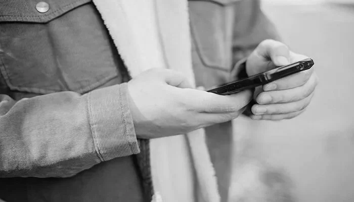 Customer using a smartphone to receive business text messages, representing SMS marketing, automated messaging, appointment reminders, and customer engagement services.