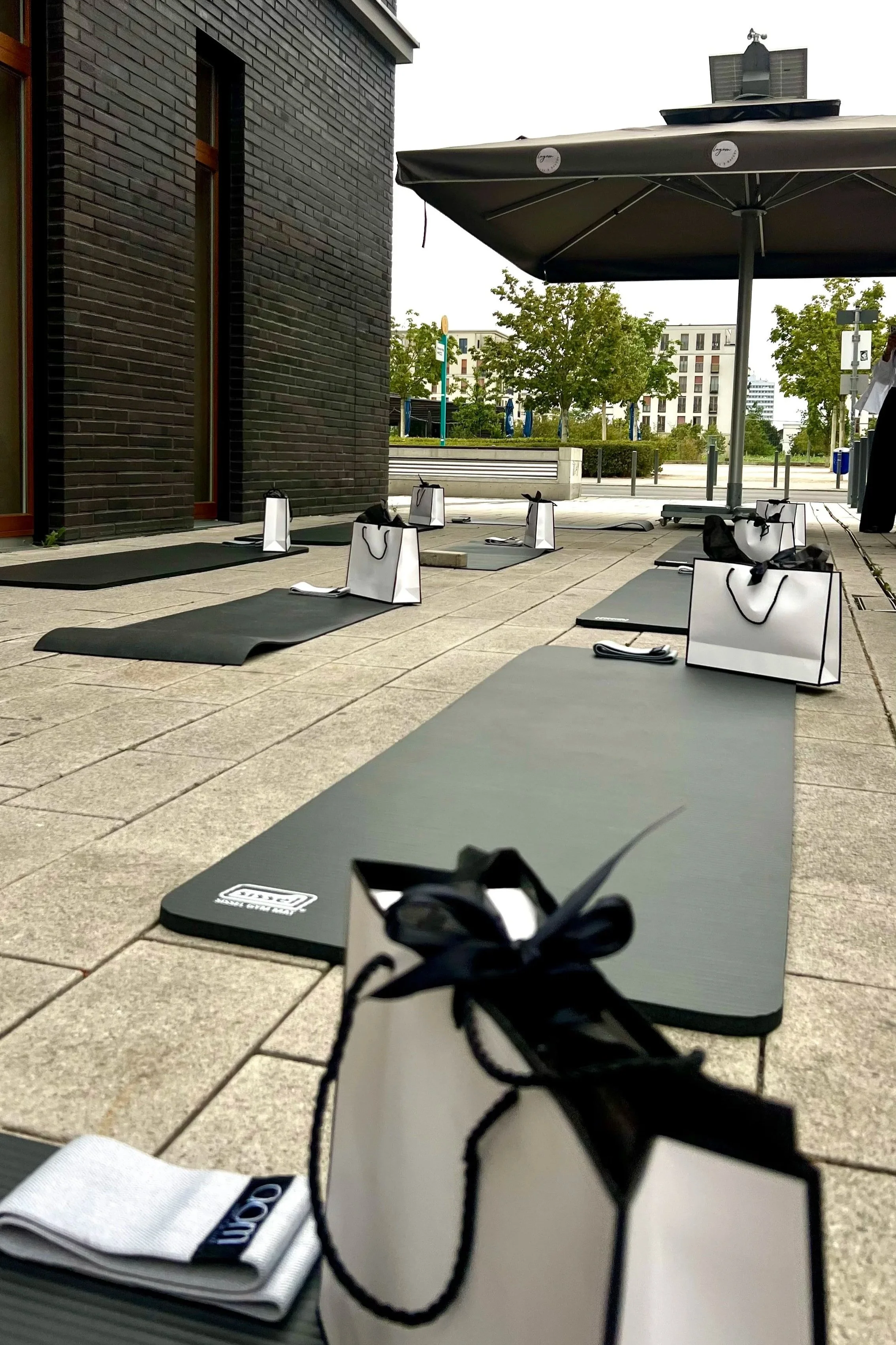 Yoga-Matten, Taschen, Handtücher und Wasserflaschen im Freien auf einer Terrasse. Es scheint eine Yoga- oder Meditationssitzung vorbereitet zu werden.