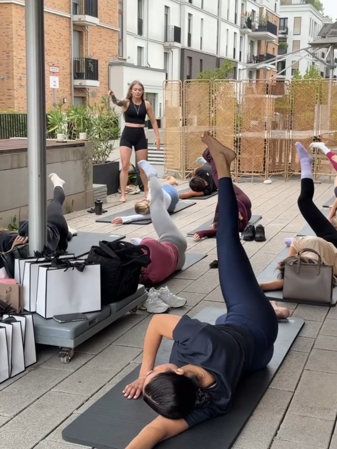 Gruppentraining im Freien mit Frauen beim Yoga auf Matten vor einer modernen Wohnanlage