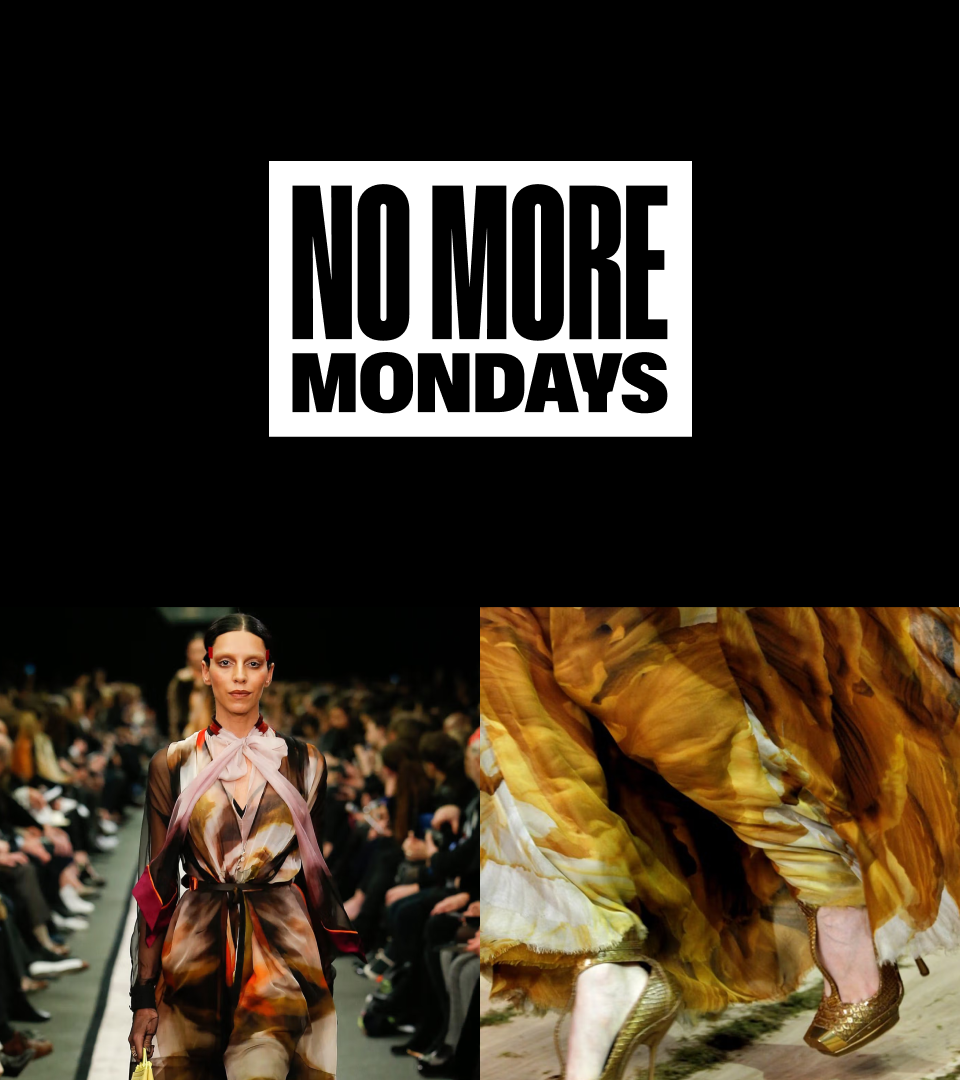 A fashion runway show with a model walking down the runway wearing a colorful, abstract patterned dress. The audience is seated on both sides of the runway, and the focus is on the model's attire and the event.