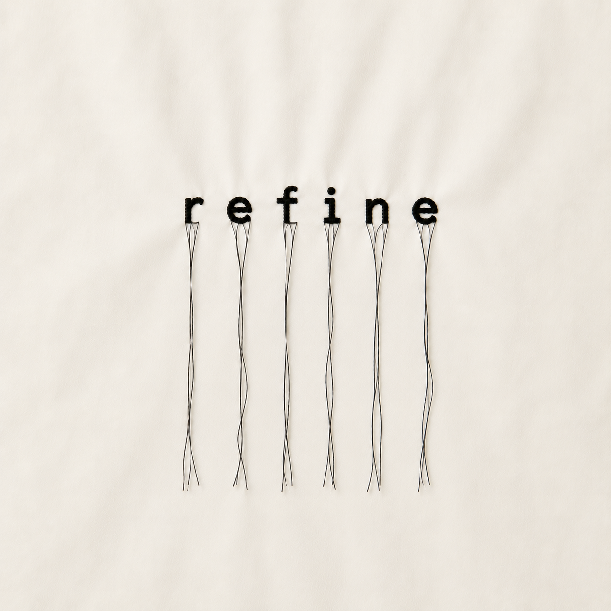 White wall with the word 'refine' spelled out in black letters, with each letter attached to thin black wires hanging downward.