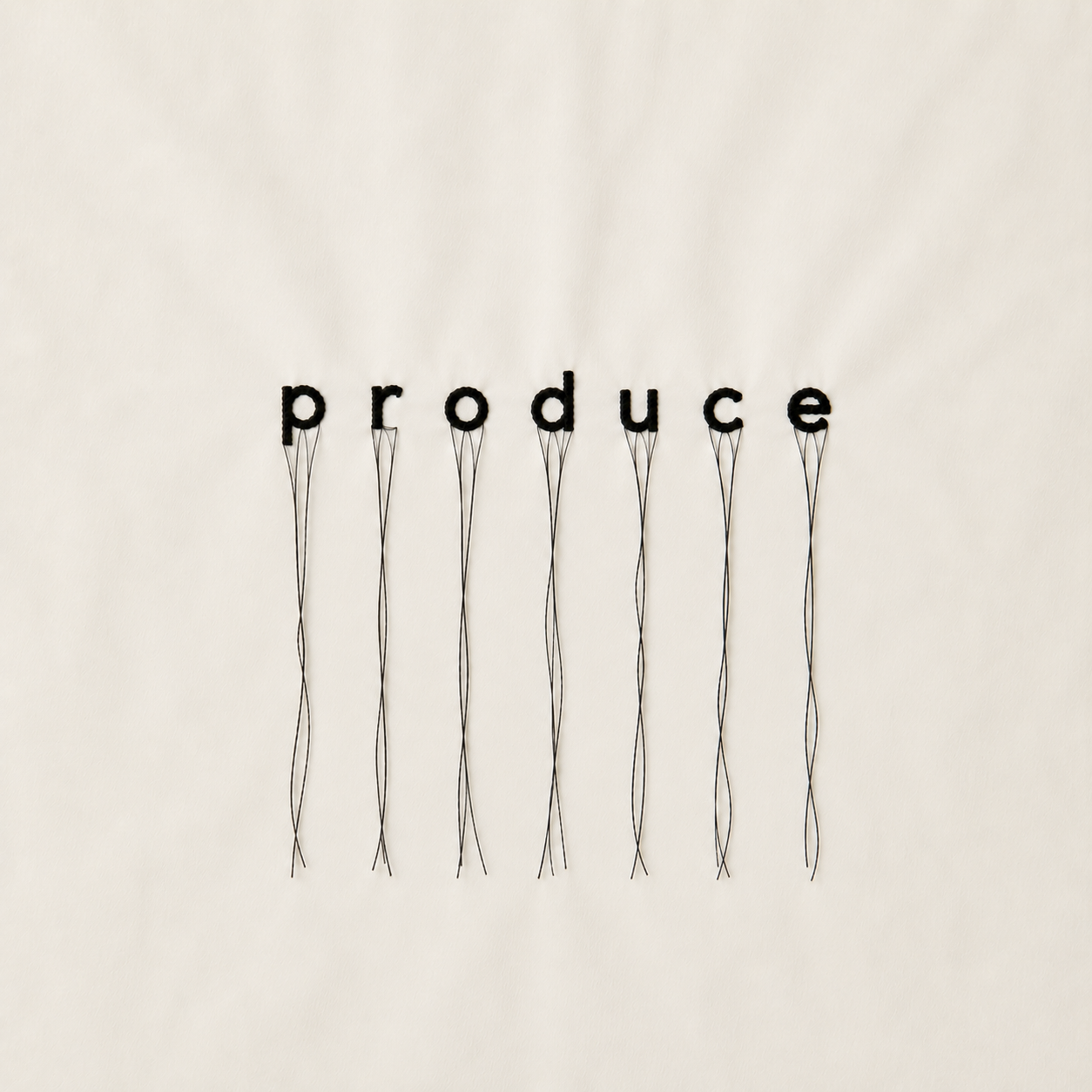 The word 'produce' spelled out with black push pins on a wall, with thin wires hanging down from each letter.