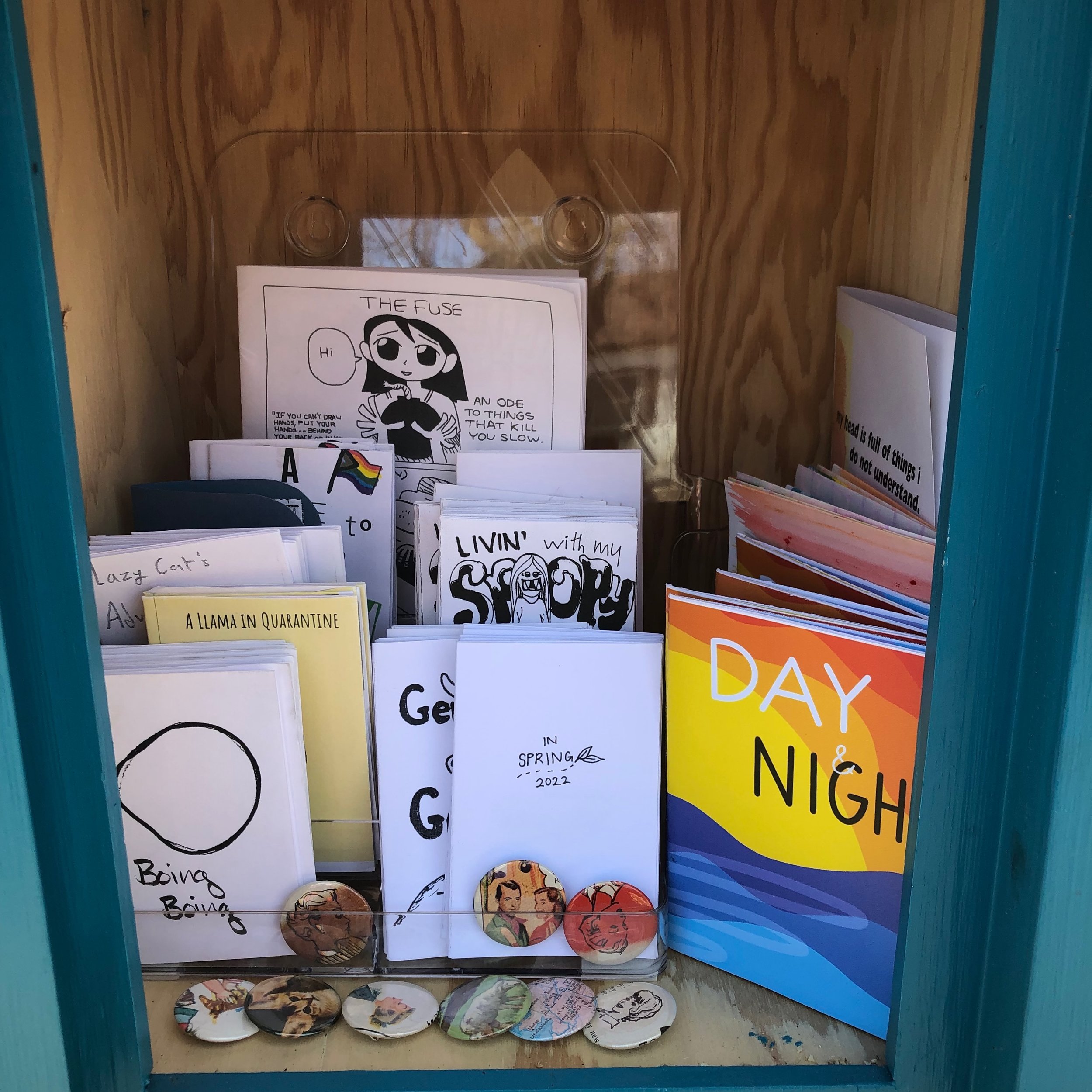 Many zines and handmade buttons in free little zine library