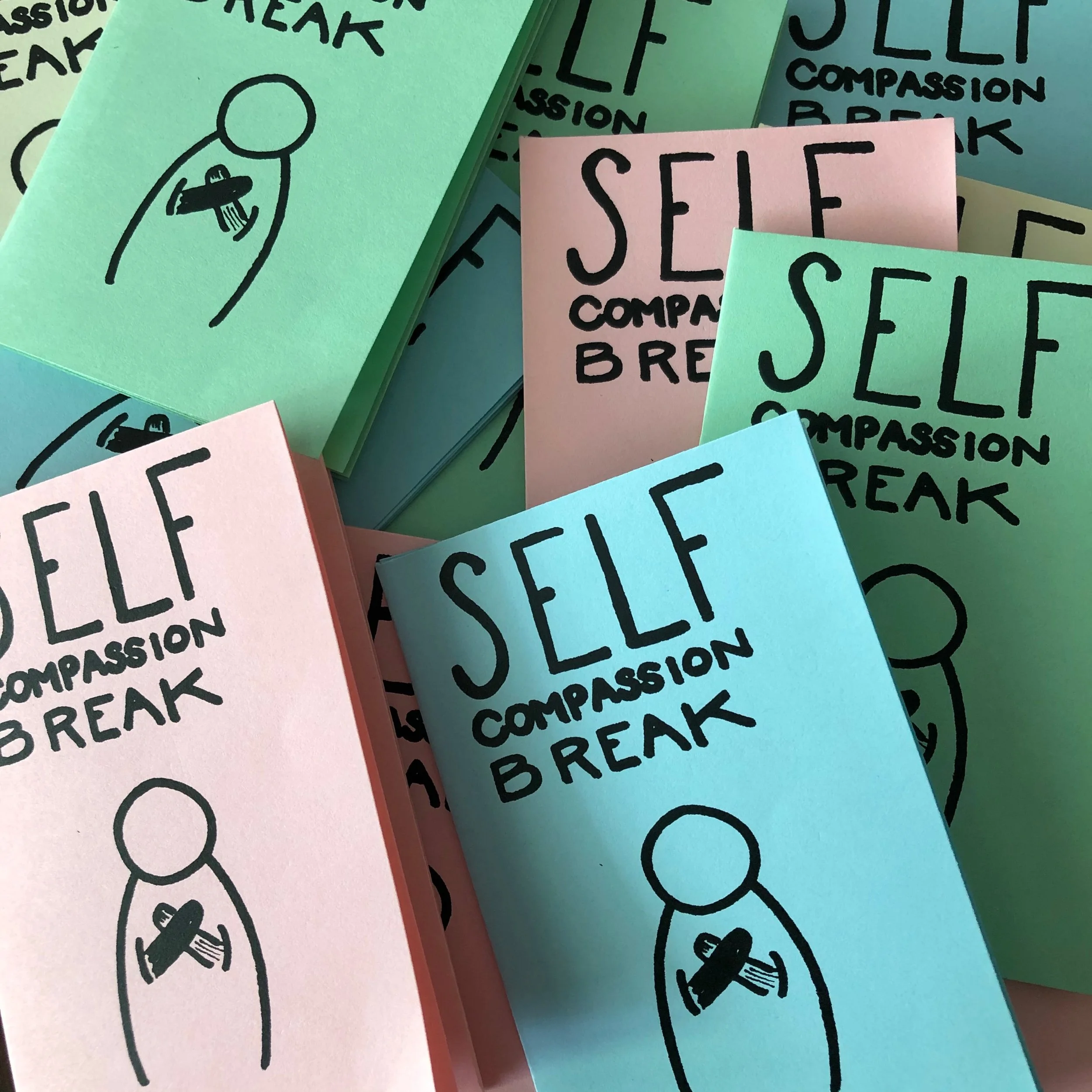 A pile of multicolored copies of the Self Compassion Break zine