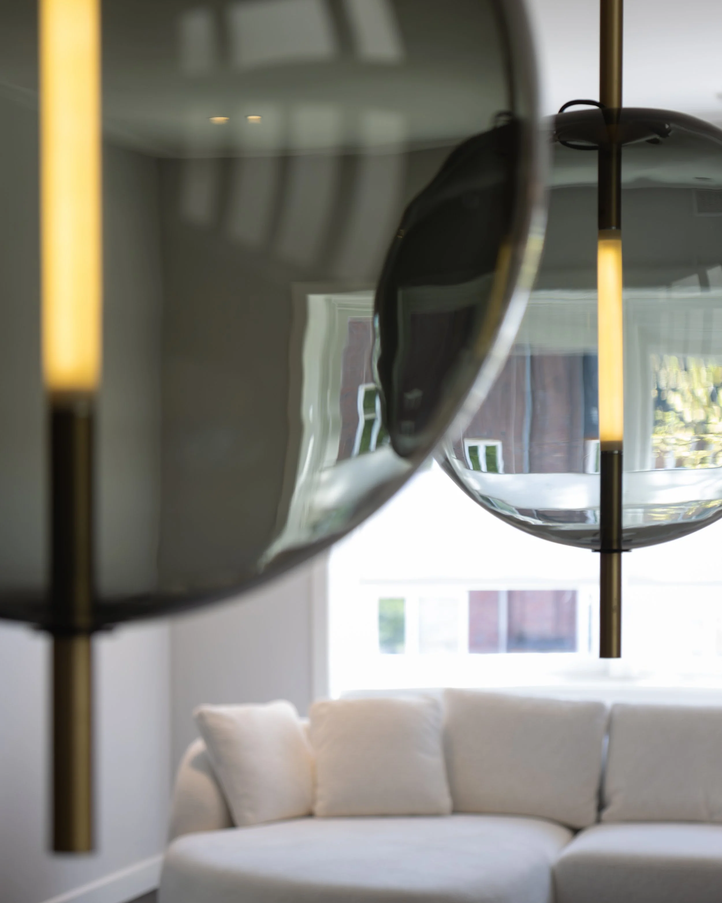 A white sofa with cushions in a living room with natural light coming through a large window.
