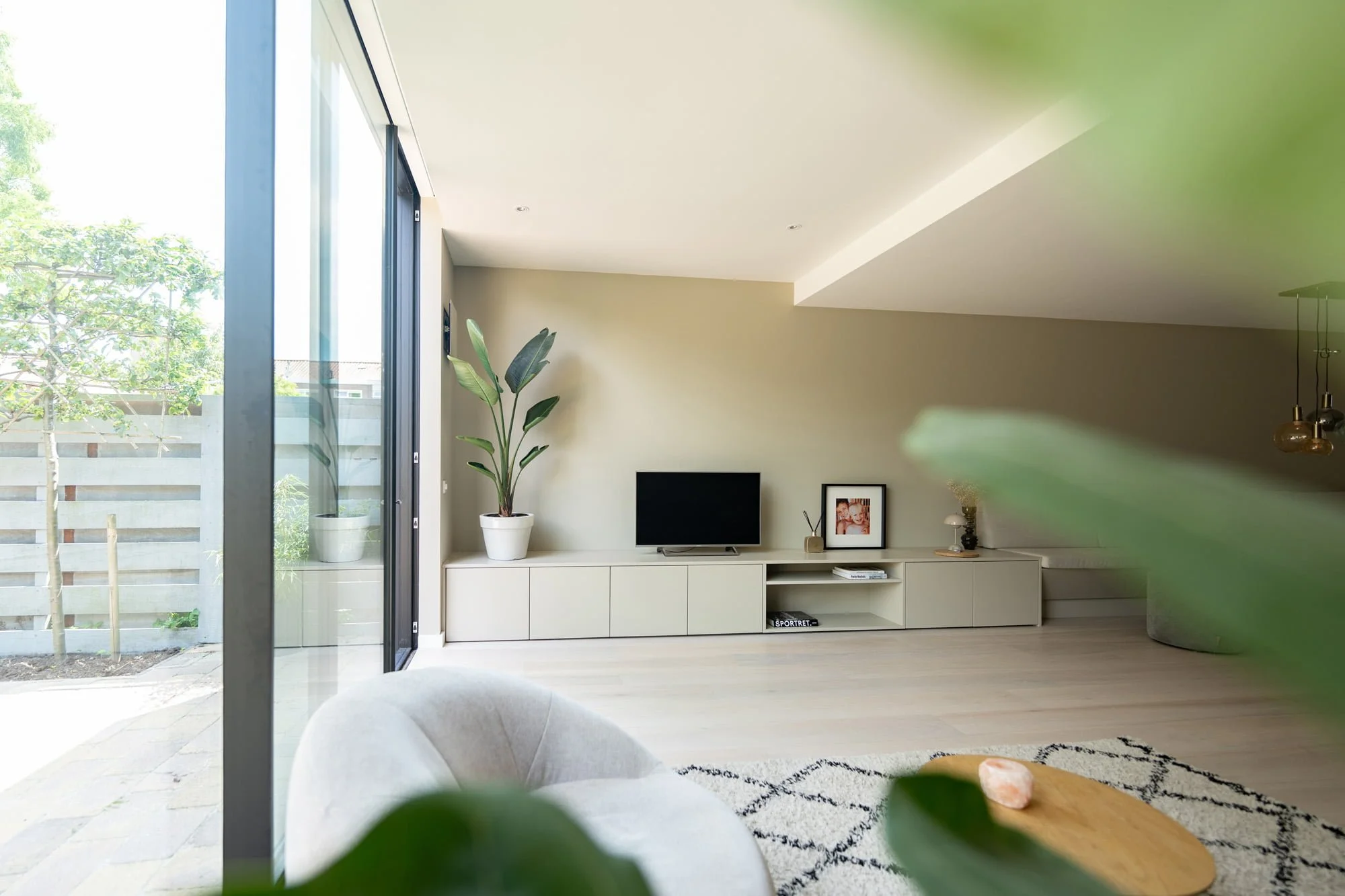 Bright living room with garden views, soft neutral interior and green accent sofa