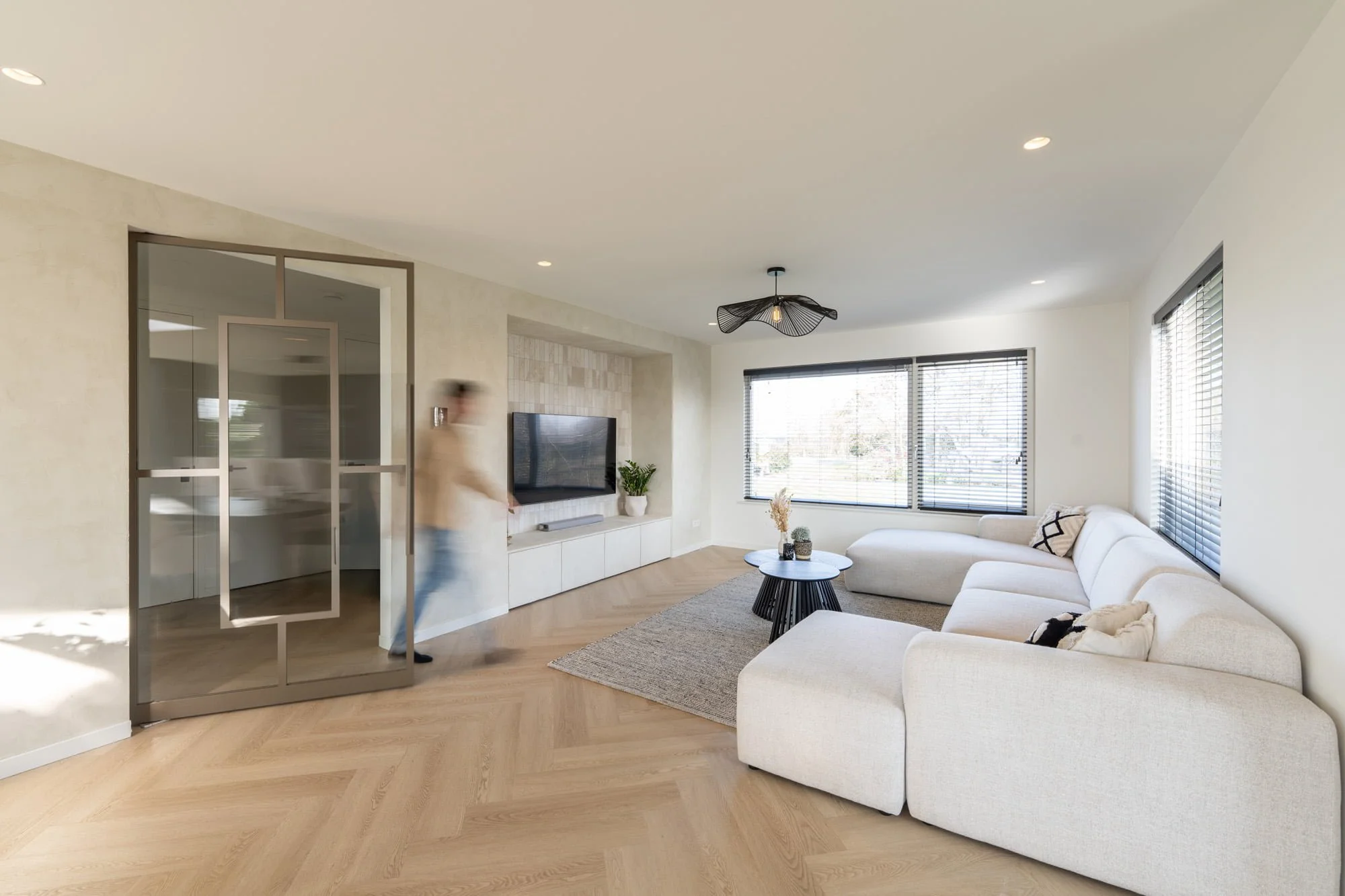 Bright living room with open kitchen, soft neutral sofa and minimal fireplace design