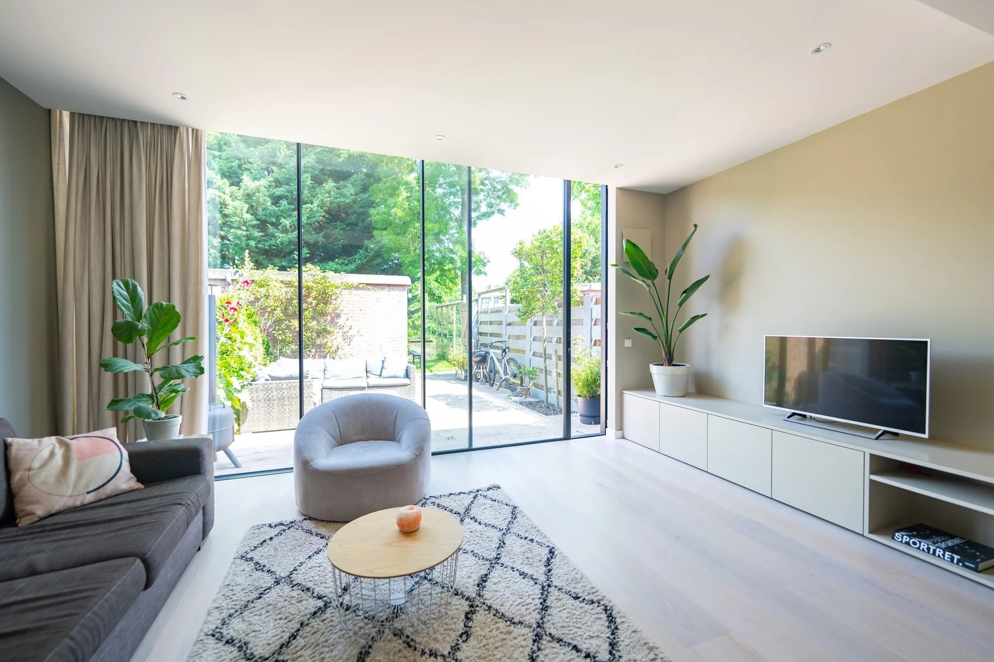 Minimal garden room with large glass opening, lounge chair and direct outdoor connection