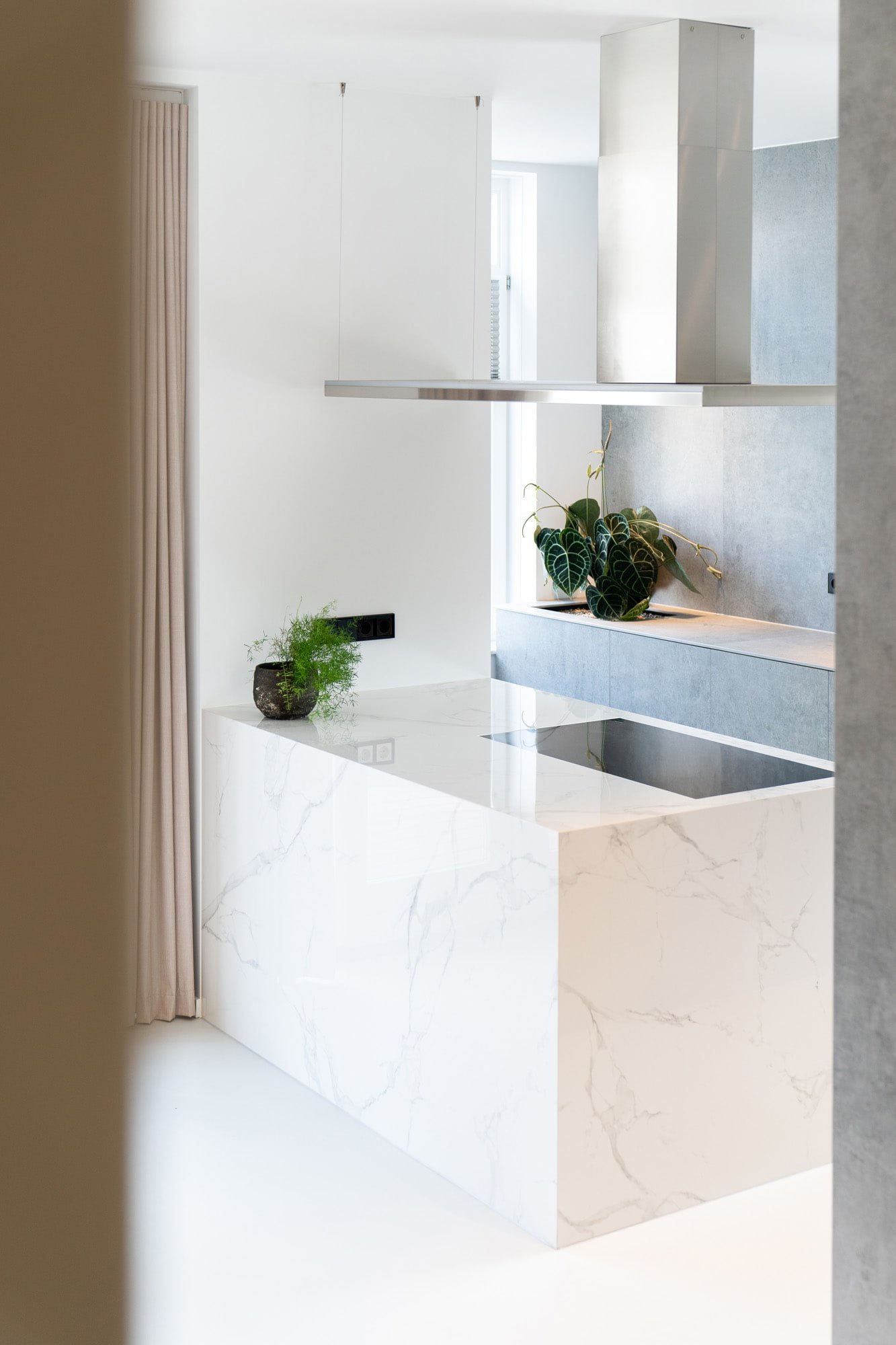 White natural stone kitchen island with integrated sink, plants and refined brass detailing