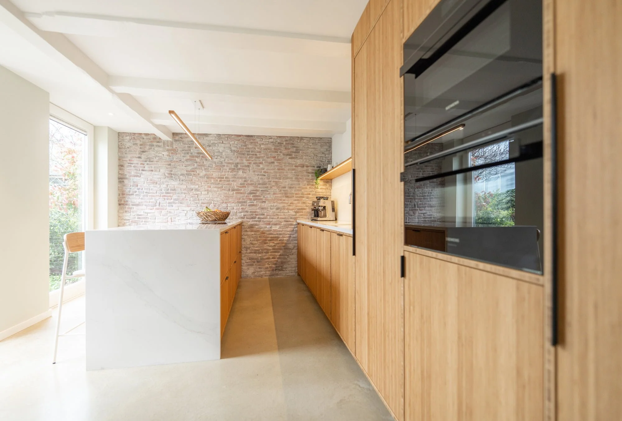 Warm oak kitchen with white worktop, brick backsplash and natural daylight