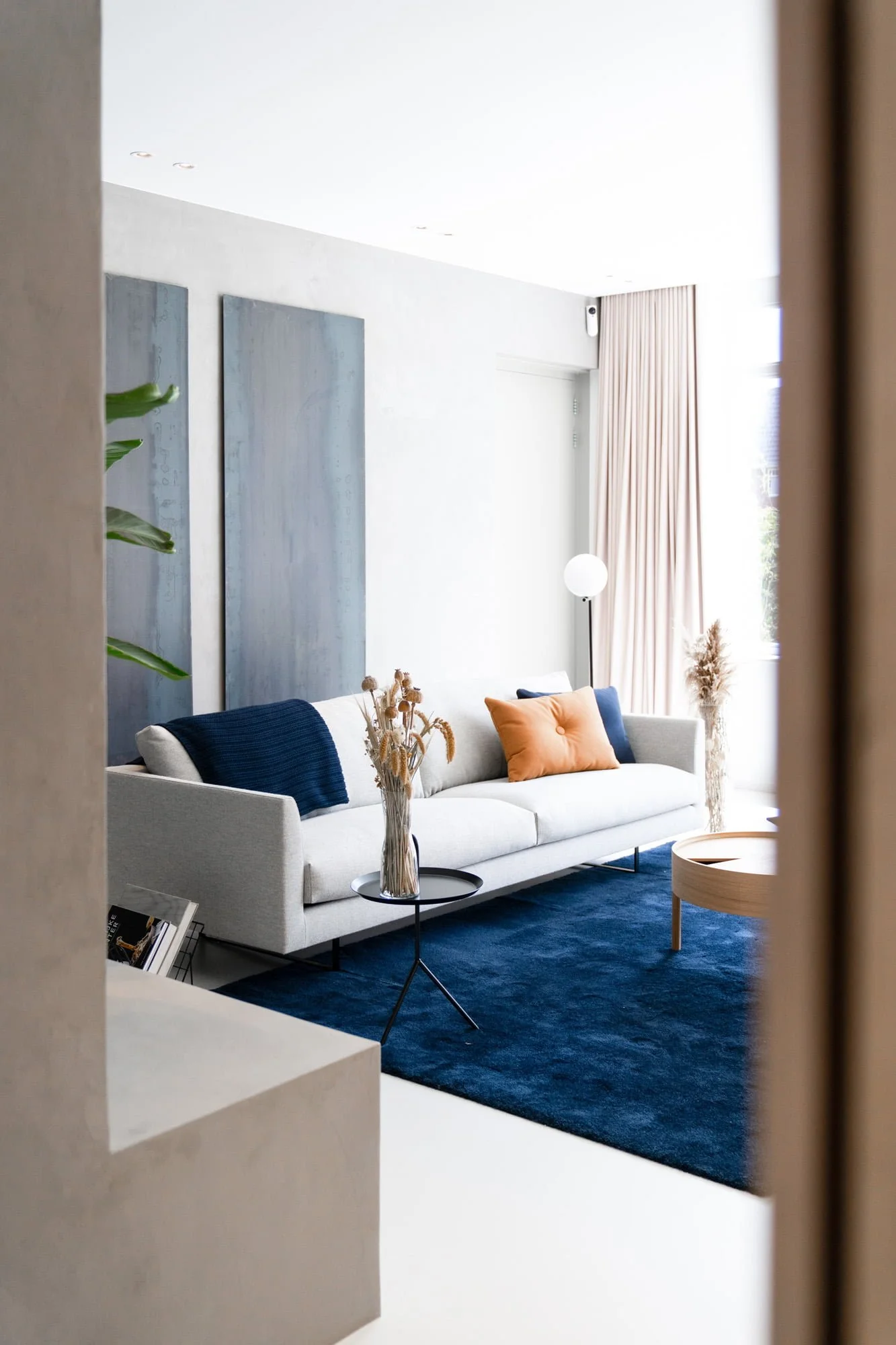 Bright living area with blue sofa, oak cabinetry and calm natural interior palette