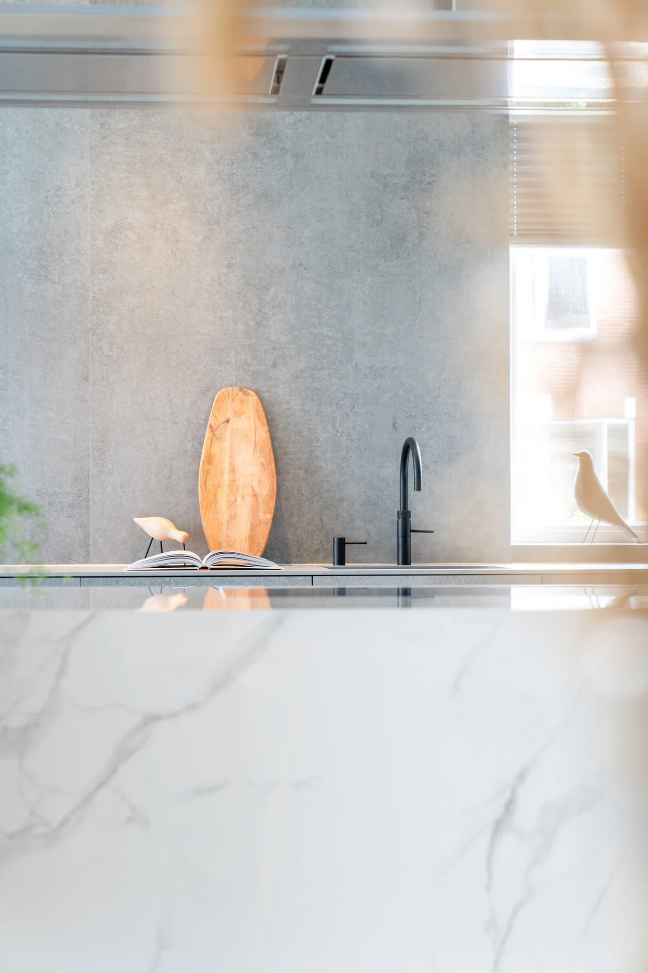 Detailed view of natural stone kitchen island with black tap and soft material styling
