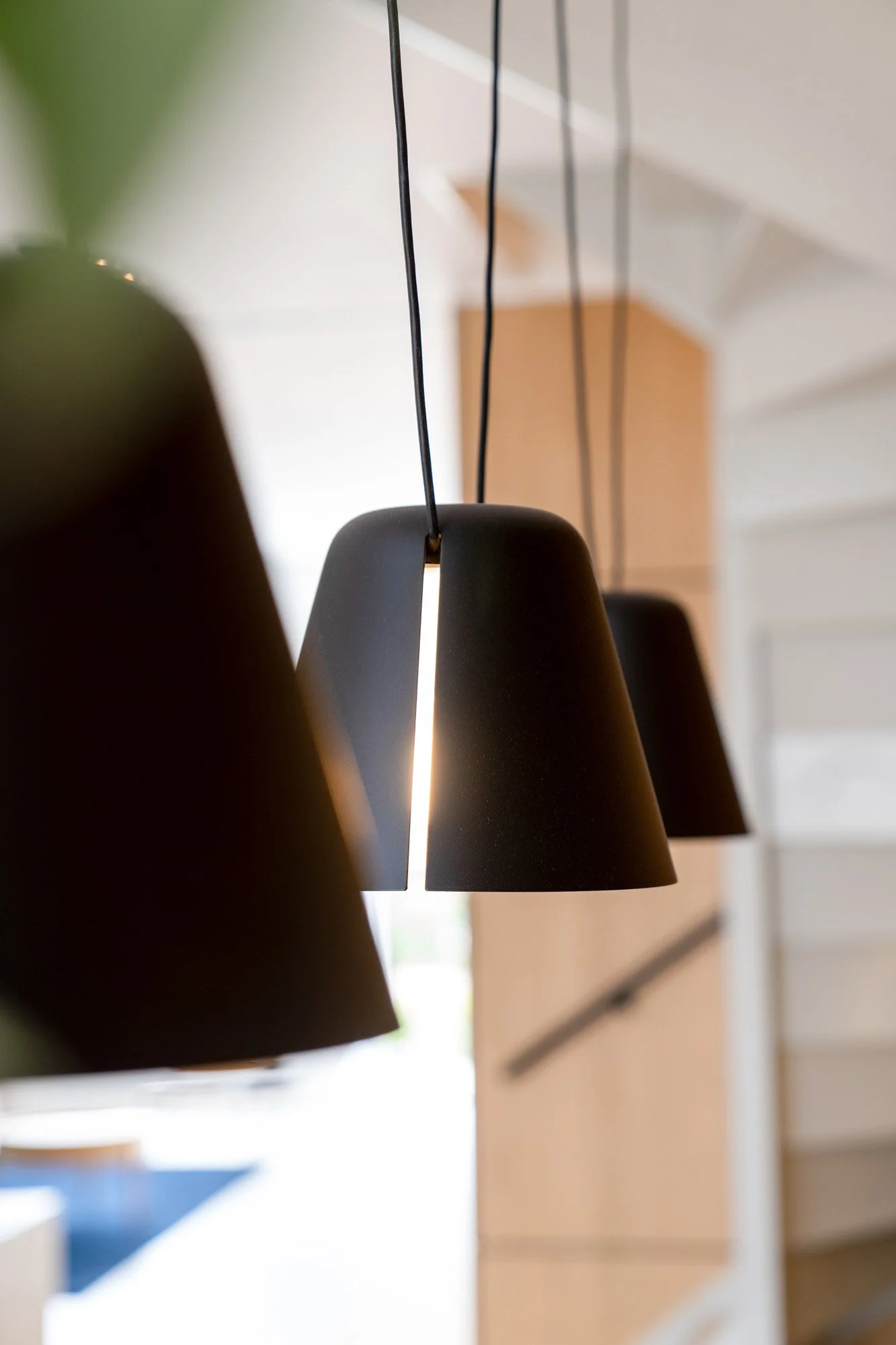 Black pendant lights above a refined dining area with oak cabinetry and natural daylight