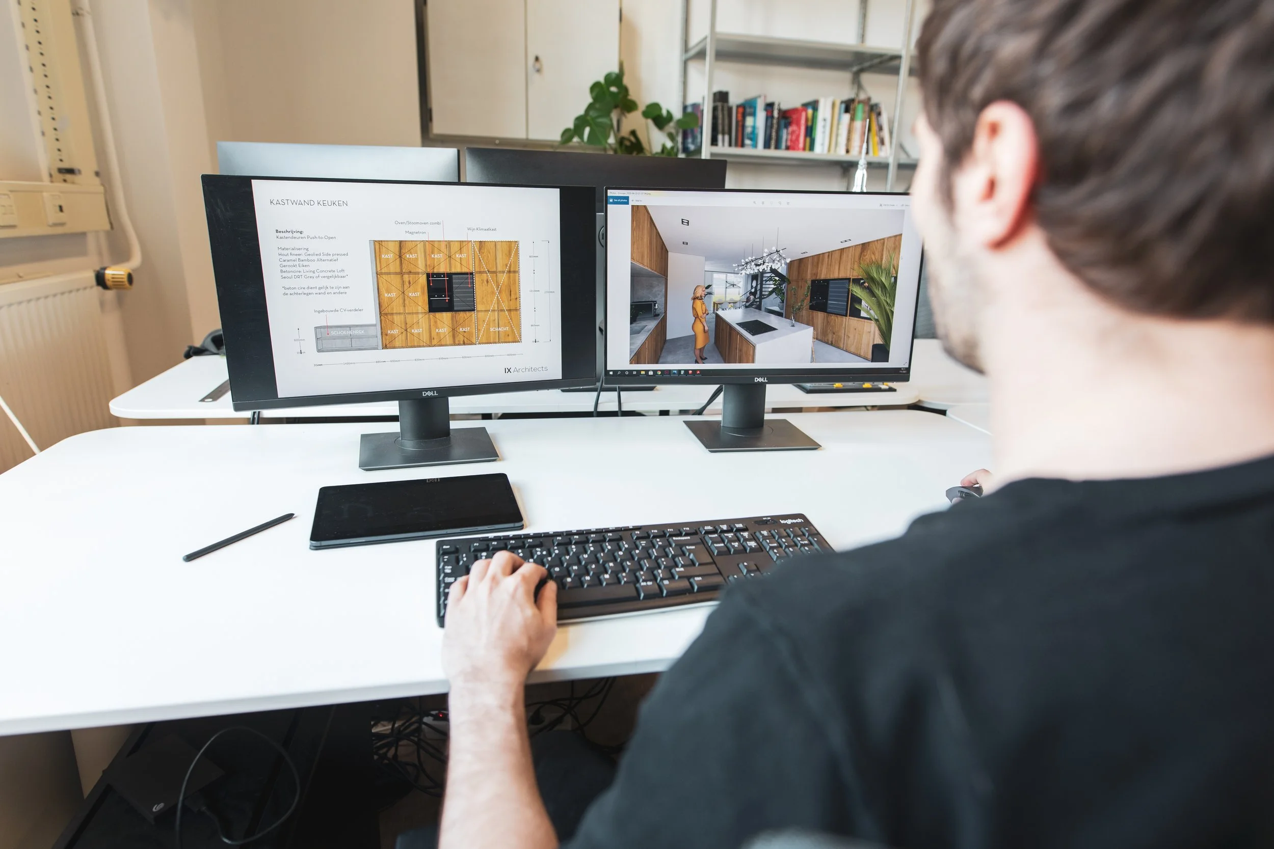 A man is working at a desk with dual computer monitors, one displaying design plans and the other showing interior space visualization, in an office with bookshelves and a radiator.