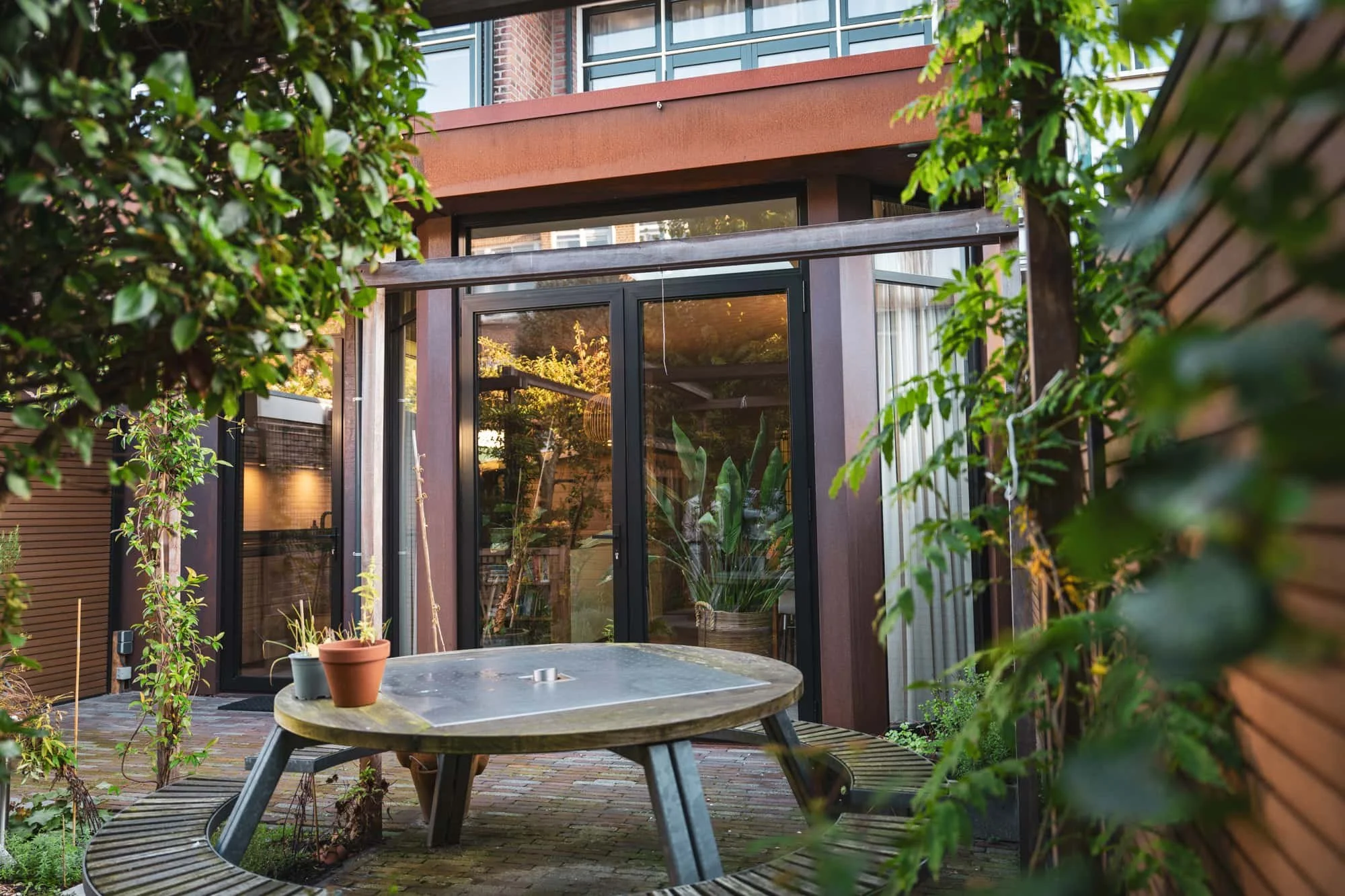 Garden terrace with wooden picnic table, corten steel facade, Vondellaan