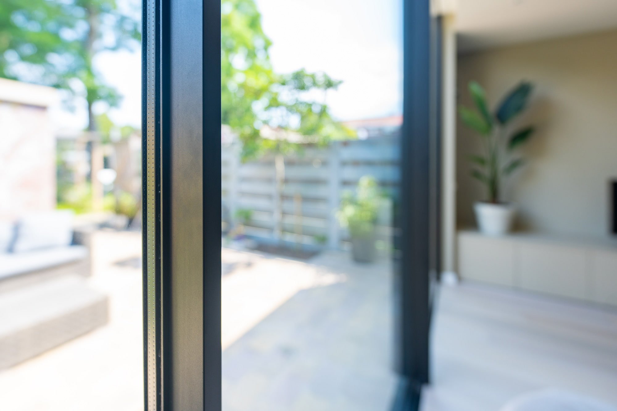 Open sliding door detail with black frame, terrace view and natural daylight
