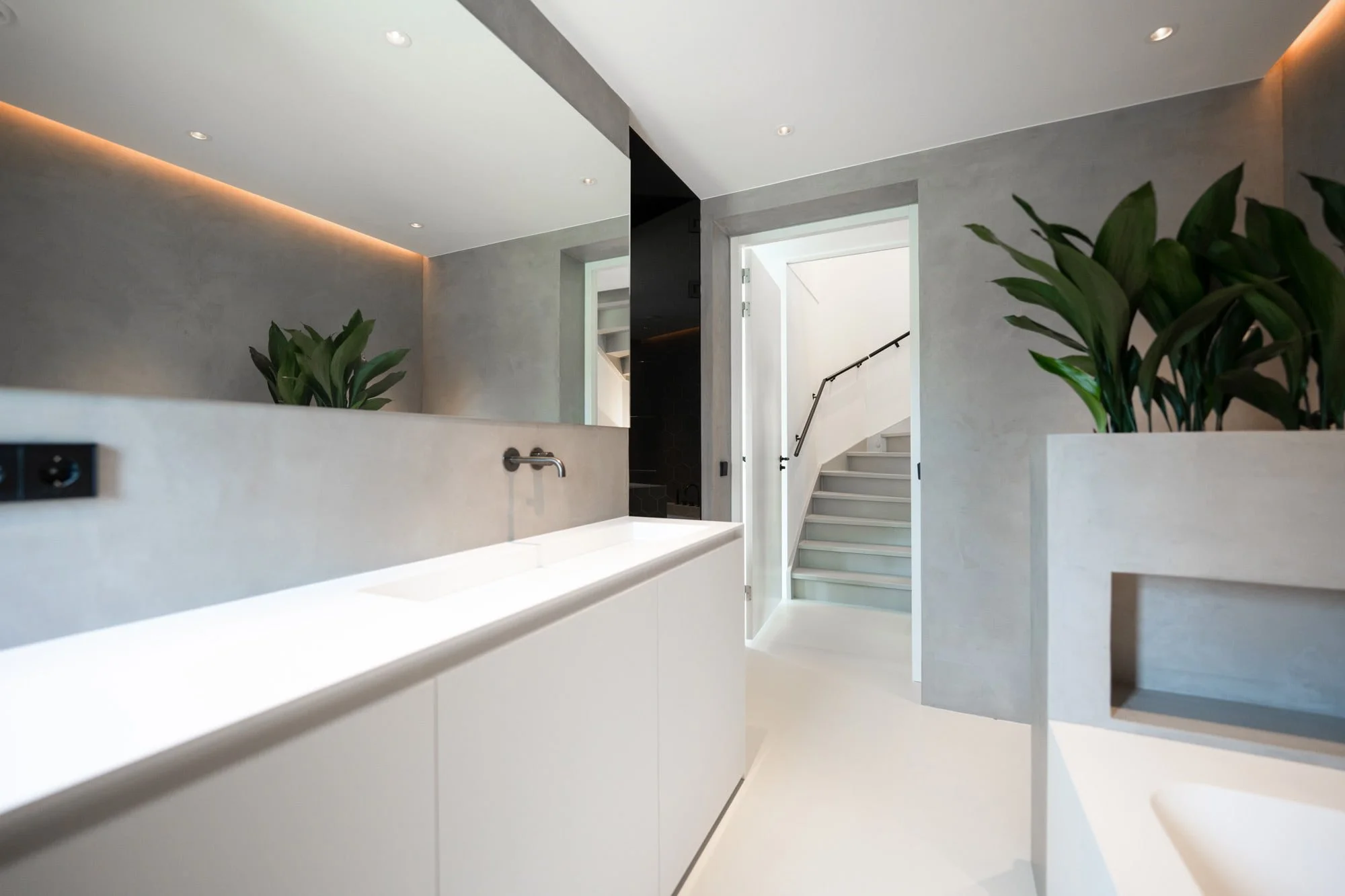 Light bathroom interior with freestanding bathtub, soft grey walls and greenery