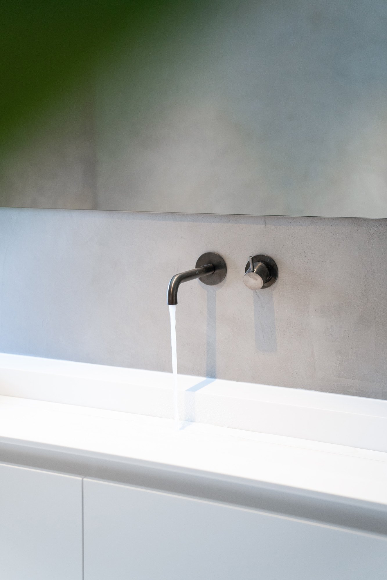 Minimal wall mounted bathroom taps with textured grey wall finish and white bathtub