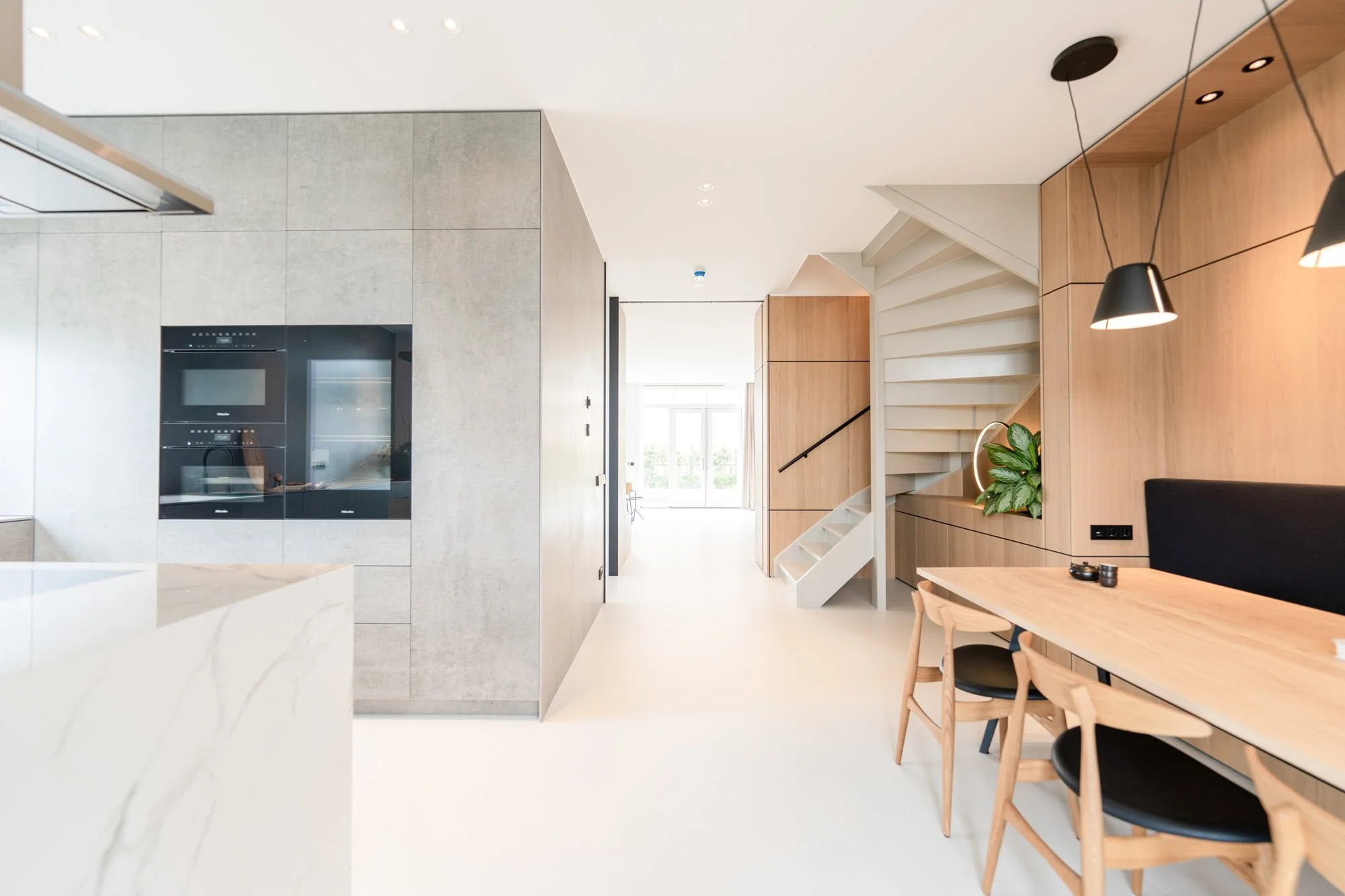 Open interior view with curved oak cabinetry, white floor and light kitchen design